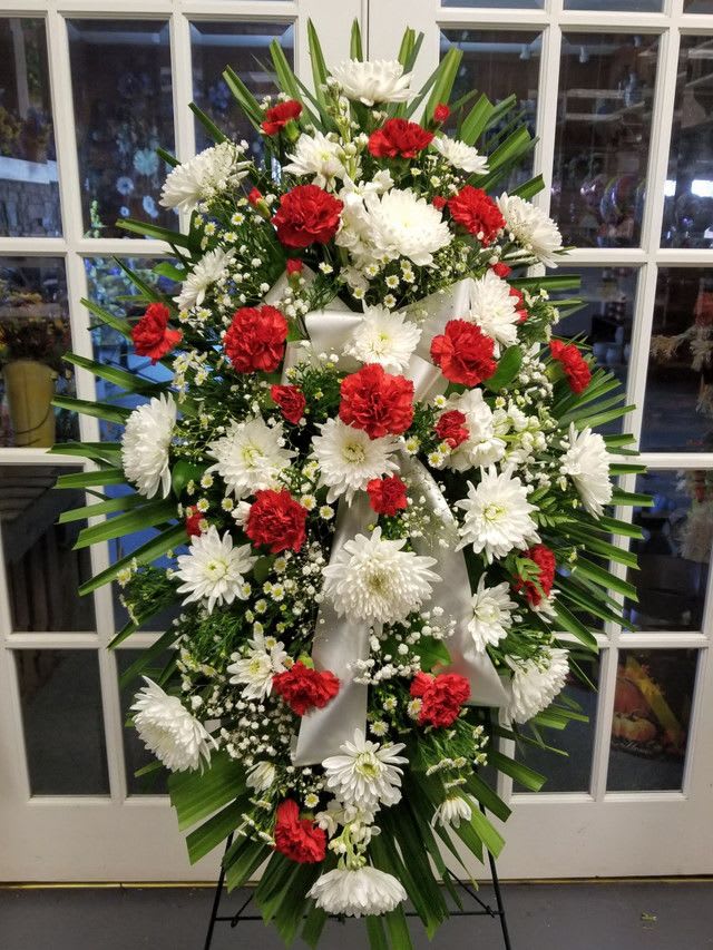 Standing floral spray with red and white flowers on a white ribbon