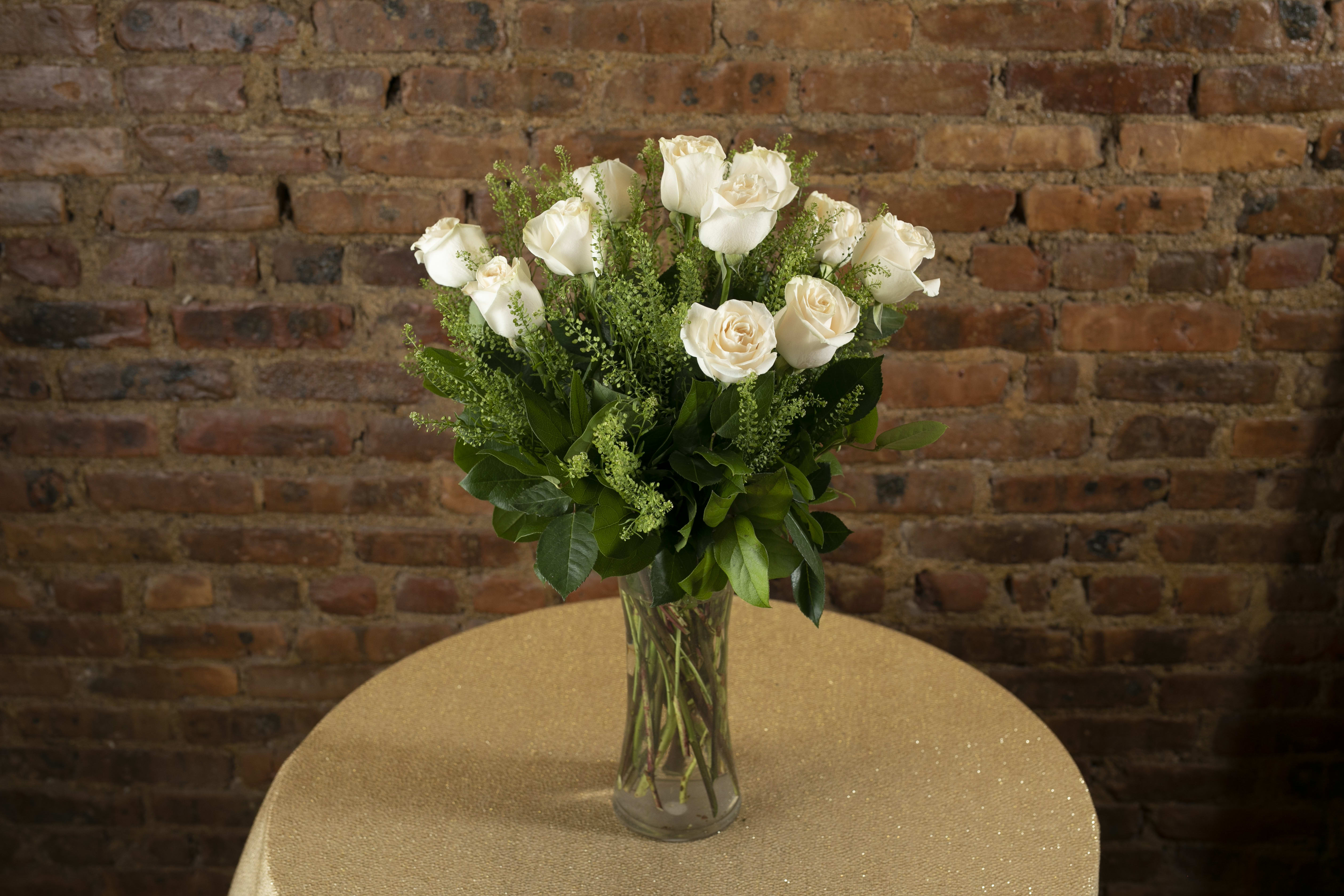 White roses in a clear glass vase on a table