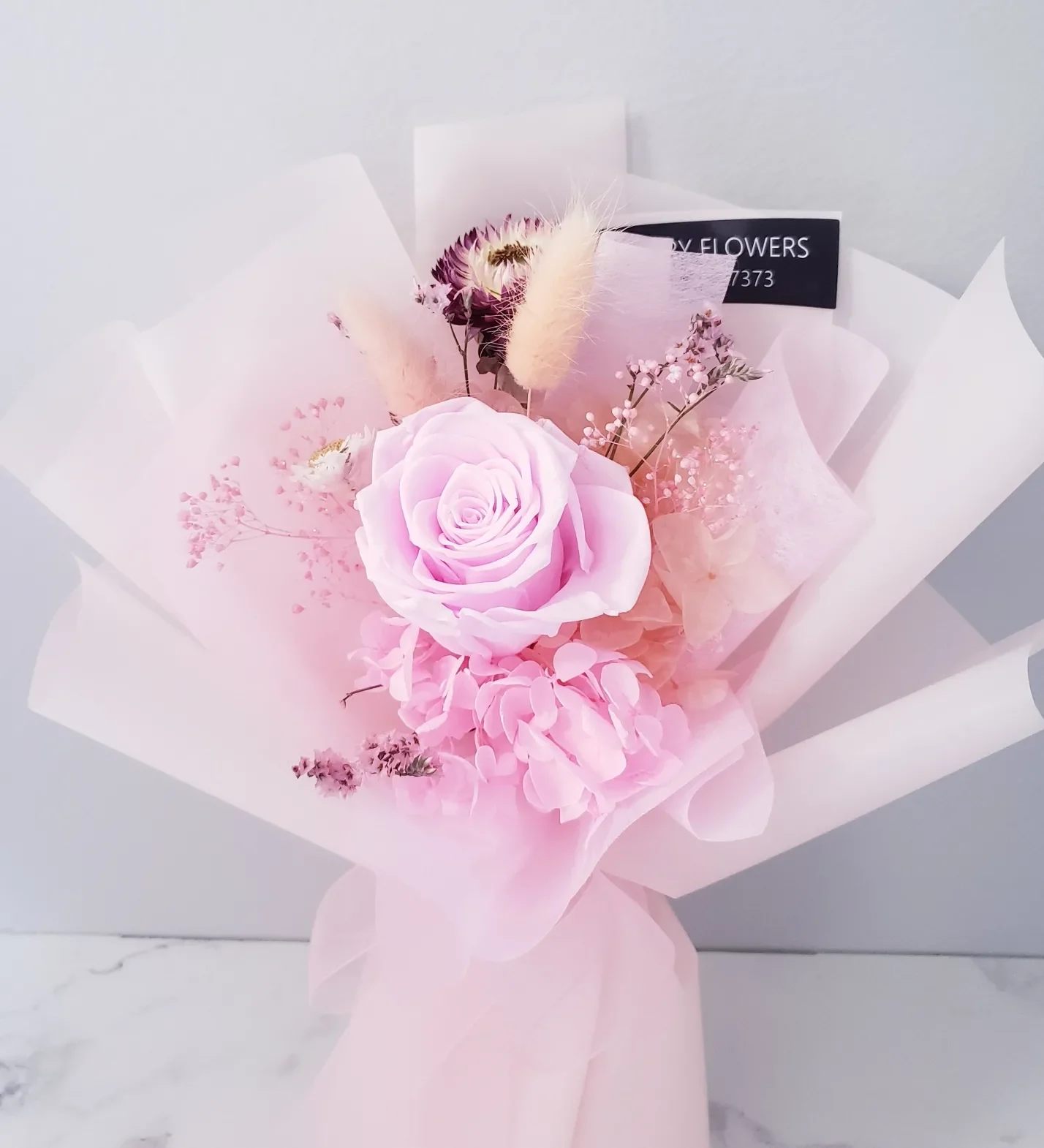 Pink rose bouquet with hydrangea and delicate filler flowers wrapped in pale pink paper