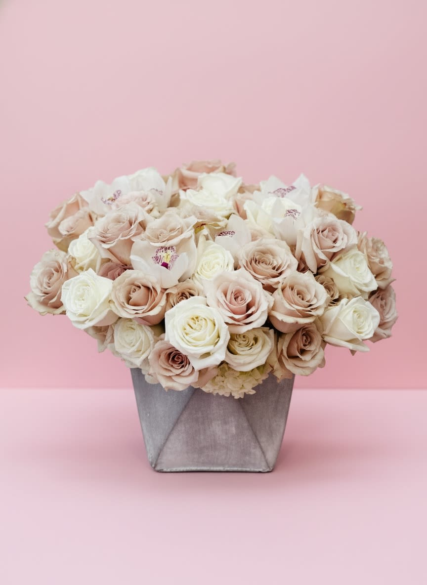 Blush Elegance - A timeless arrangement featuring luxurious blush and ivory roses accented with delicate white cymbidium orchids, artfully arranged in a modern silver velvet keepsake box. Soft, romantic, and effortlessly elegant, this design is perfect for birthdays, anniversaries, baby showers, sympathy, or simply making someone feel special. The neutral palette complements any home or event décor with grace and sophistication.