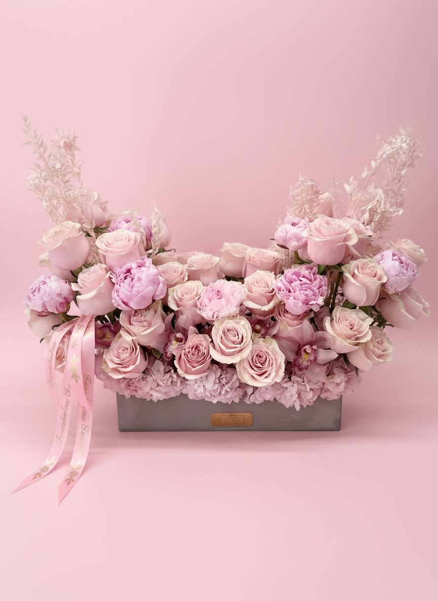 Blushing Roses  - **Elegant Concrete Base Arrangement with Blush Roses and Accent Filler Flowers**  Elevate your upcoming event with our stunning concrete base arrangement, featuring a harmonious blend of soft blush roses and delicate accent filler flowers. This modern design exudes sophistication, making it the perfect centerpiece for weddings, parties, or any special occasion.  Crafted with attention to detail, the concrete base adds an industrial yet chic touch, while the gentle hues of blush roses bring warmth and romance to your setting. The accent filler flowers complement the roses, adding texture and depth to the arrangement, creating a visually captivating display that will leave a lasting impression on your guests.  Whether placed on dining tables, entryways, or as part of a larger floral display, this arrangement is sure to enhance the ambiance of your event. Celebrate life’s beautiful moments with a centerpiece that embodies elegance and style. Make your event unforgettable with our exquisite concrete base arrangement!