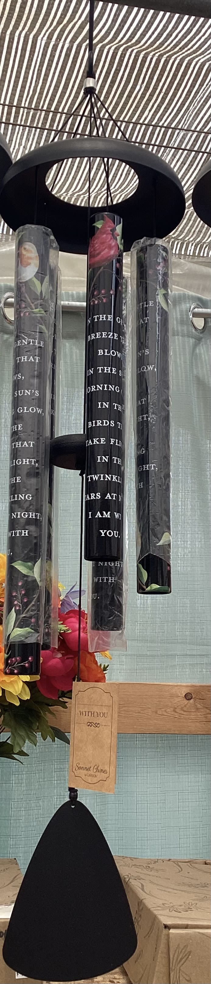 Hanging black wind chimes with floral accents and a small wooden tag