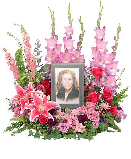 Always In Our Hearts - Ease the mourning of the loss of a loved one with the stunning Always In Our Hearts memorial arrangement. Stargazer lilies, roses, and carnations in vibrant pink tones designed to surround a photograph; perfect for celebrating the brilliant life of a special woman. Picture Frame not Included  Includes Wet Floral Foam Wreath, Foliage: Variegated Pittosporum, Ivy, Sword Fern, Silver Dollar Eucalyptus, Pink Roses, Hot Pink Roses, Pink Daisy Poms, Stargazer Lilies, Pink Stock, Pink Gladiolus, Pink Larkspur, Bells Of Ireland, Deep Purple Carnations, Purple Statice.