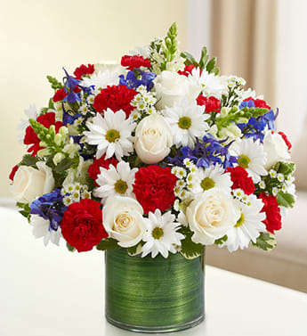 Cherished Memories - Red, White and Blue - Product ID: 95443   Send a patriotic and peaceful tribute to a beloved veteran with this truly original red, white and blue arrangement of roses, snapdragons, delphinium, carnations and more. Elegantly arranged by our florists in a classic vase to send your condolences to the home or the service. Graceful red, white and blue floral arrangement of roses, snapdragons, delphinium, carnations, daisy poms, mini carnations and monte casino, gathered with variegated pittosporum Hand-designed by our expert florists in a stylish clear glass cylinder vase wrapped with a Ti leaf ribbon; vase measures 6"H Appropriate for the service or the home of friends and family members to honor the passing of a military veteran Large arrangement measures approximately 16"H x 17"L Medium arrangement measures approximately 15"H x 16"L Small arrangement measures approximately 14"H X 15"L Our florists hand-design each arrangement, so colors, varieties, and vase may vary due to local availability