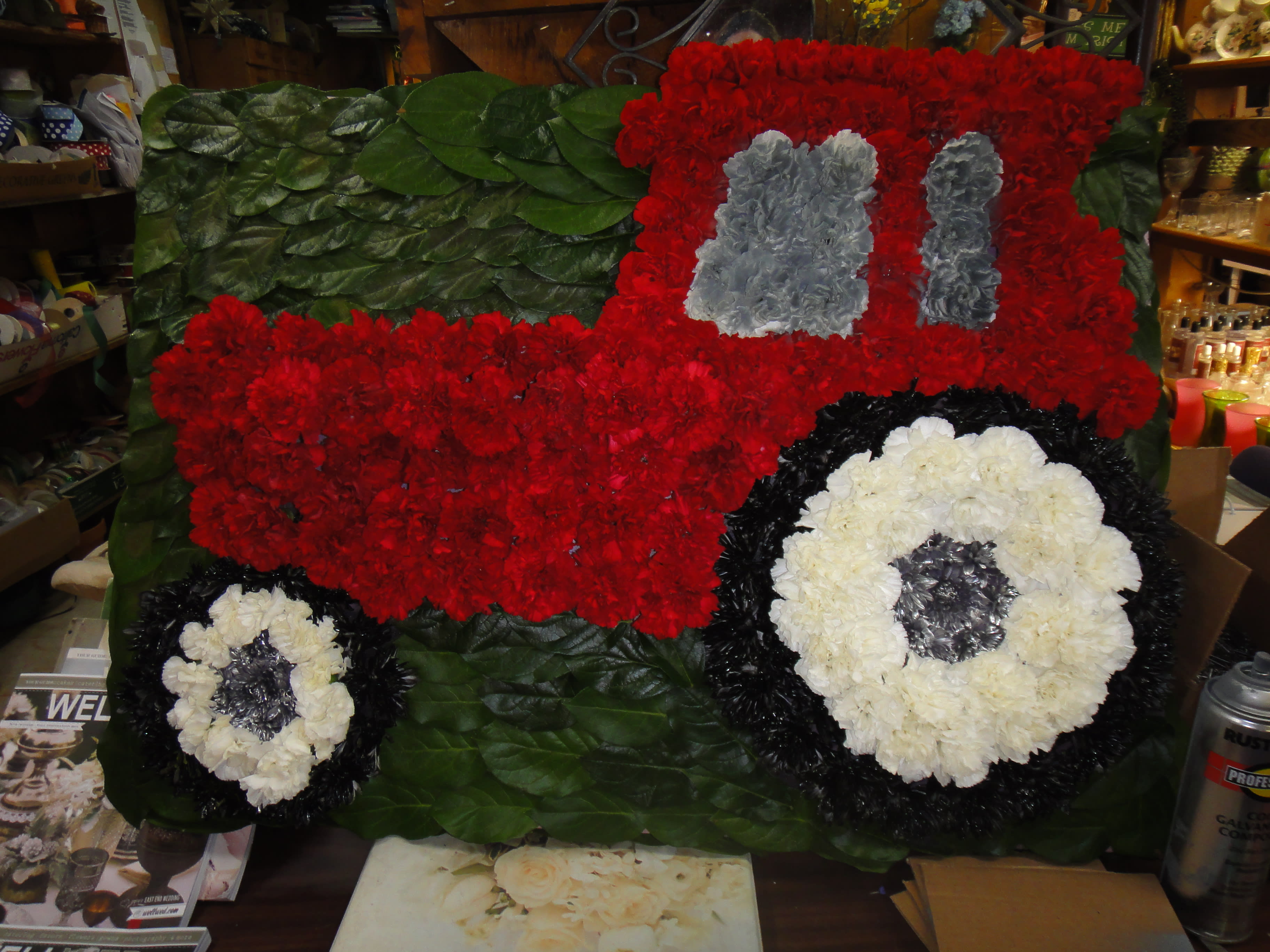Floral arrangement shaped like a red truck with white wheels
