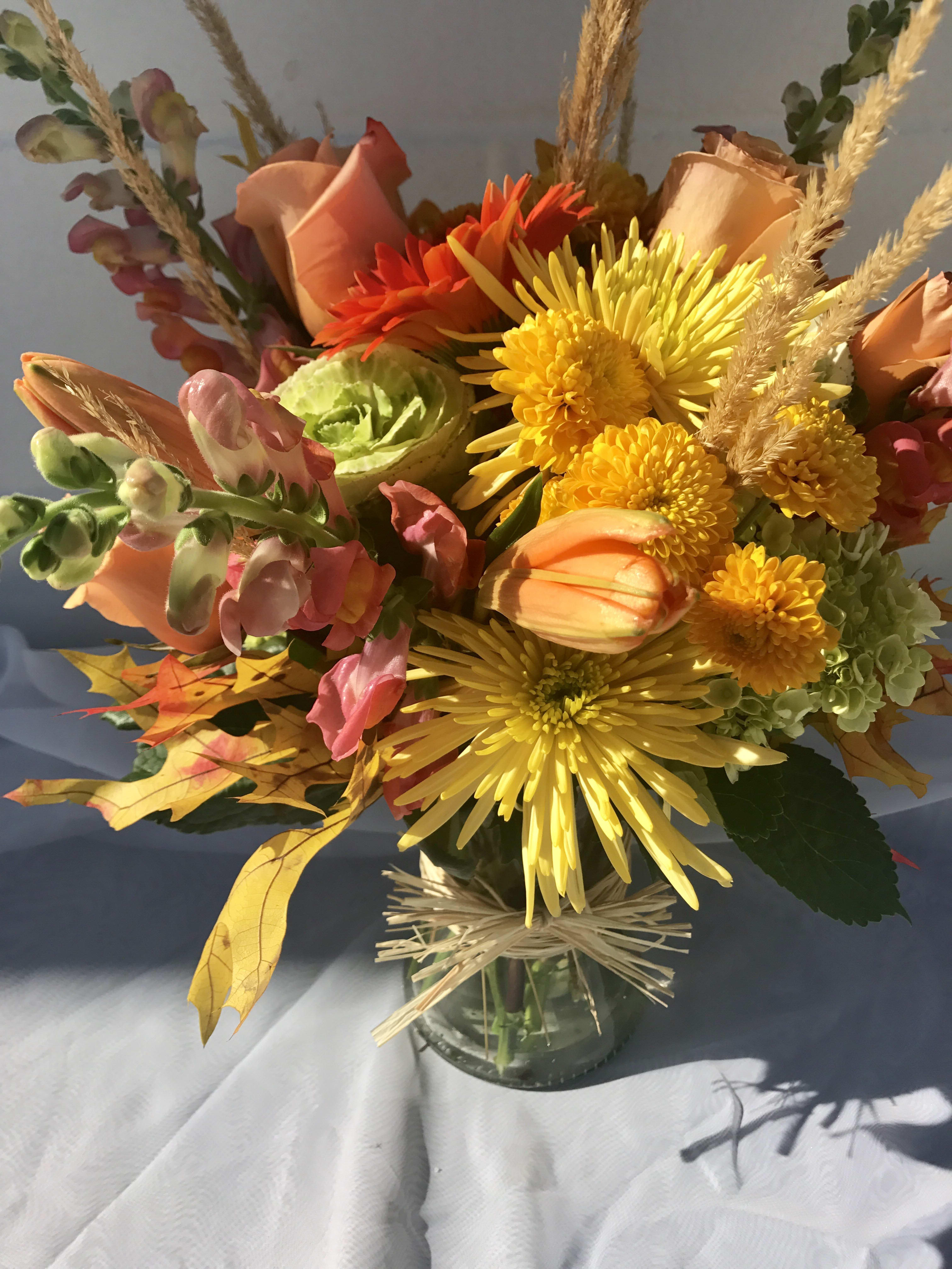 Bouquet of yellow, orange, and pink flowers in a glass vase