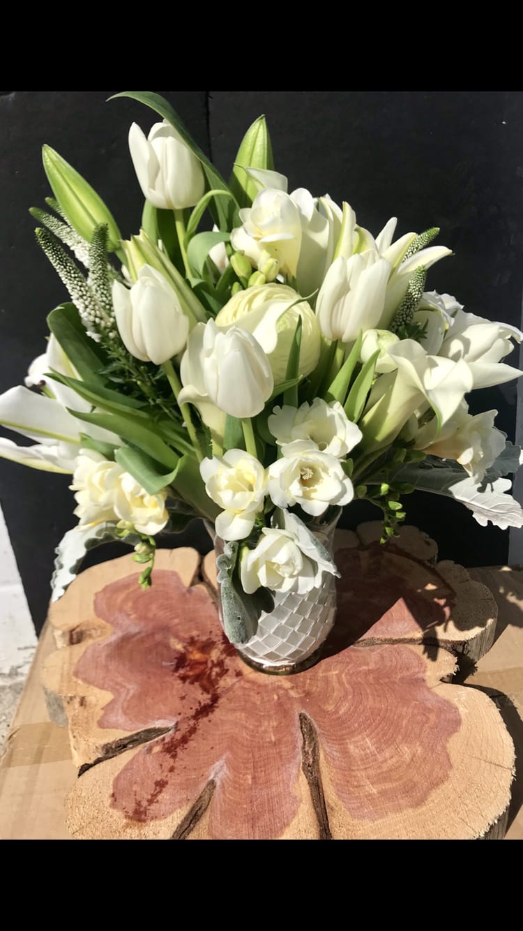 White tulips and lilies arranged in a textured white vase
