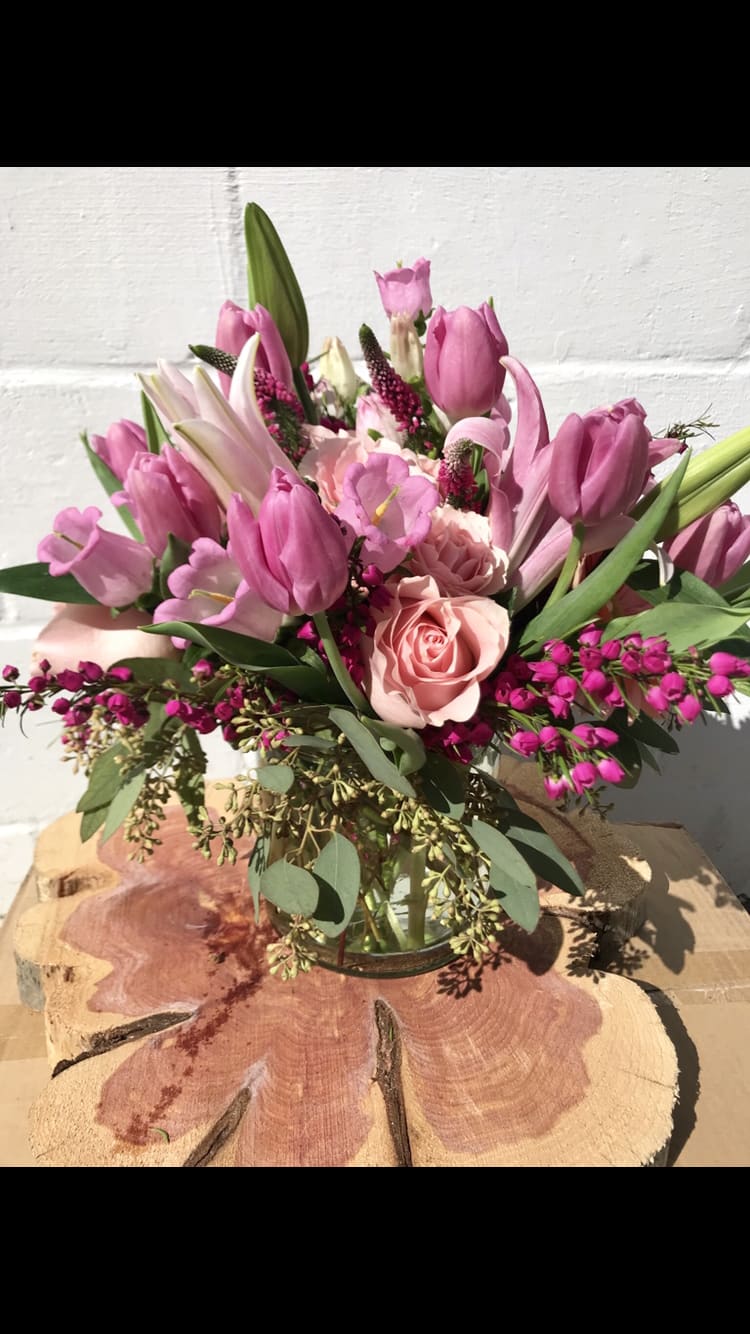 Pink tulips and roses arranged in a clear glass vase