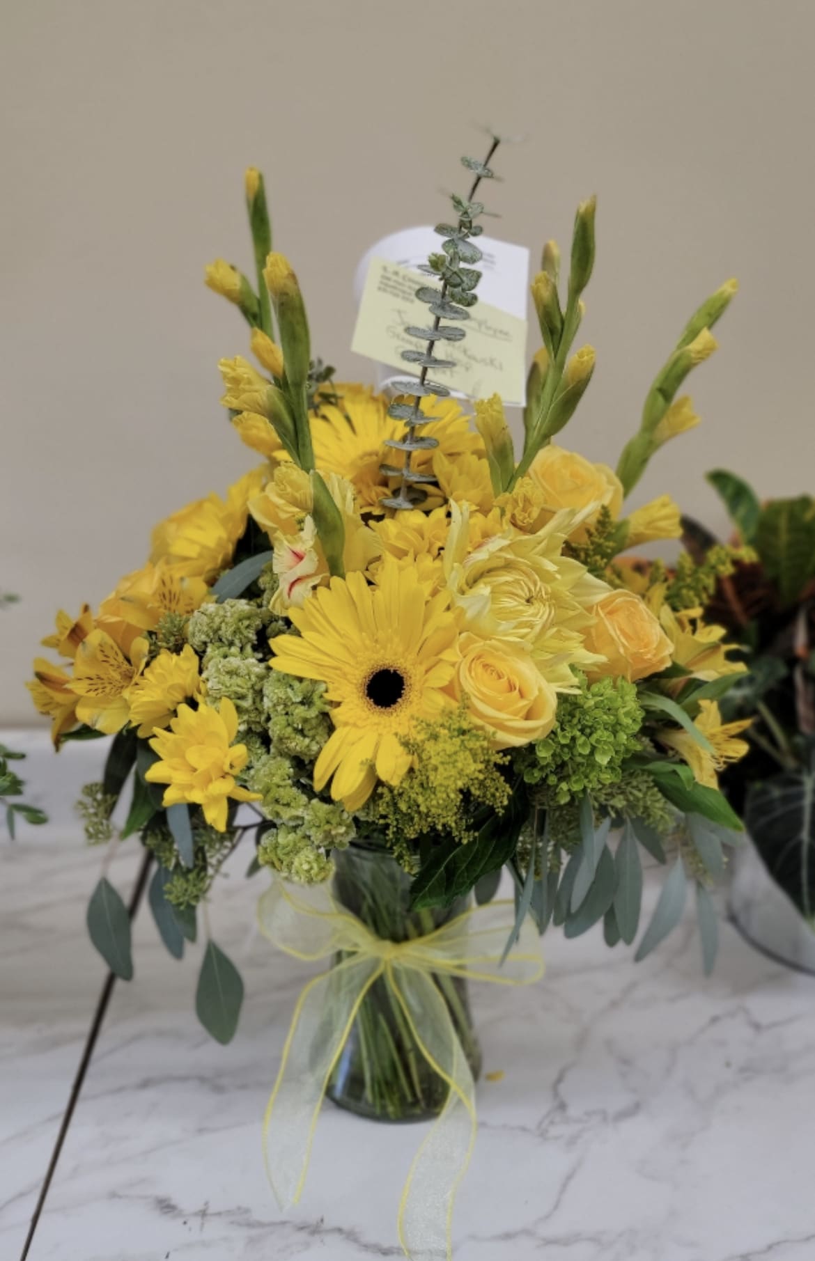 Yellow bouquet in a glass vase with gerbera daisies and roses