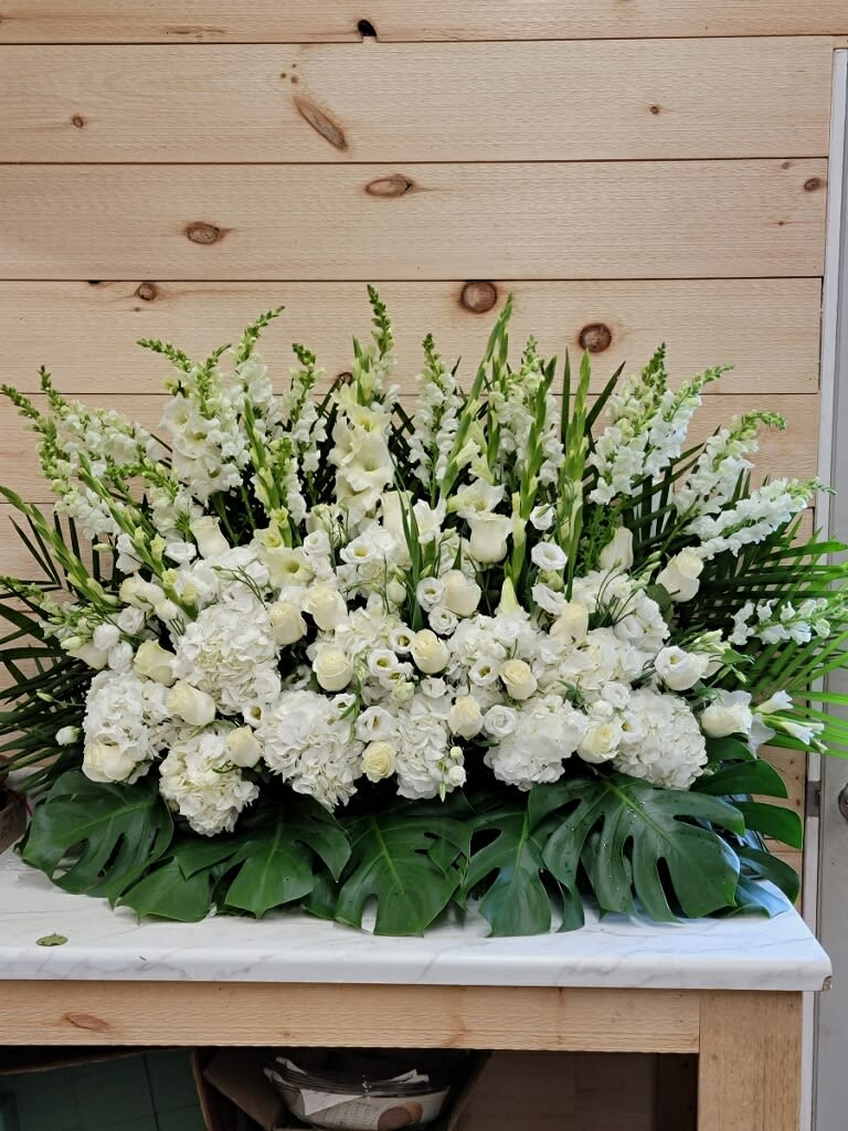 Large white floral arrangement with tall spikes and broad green leaves