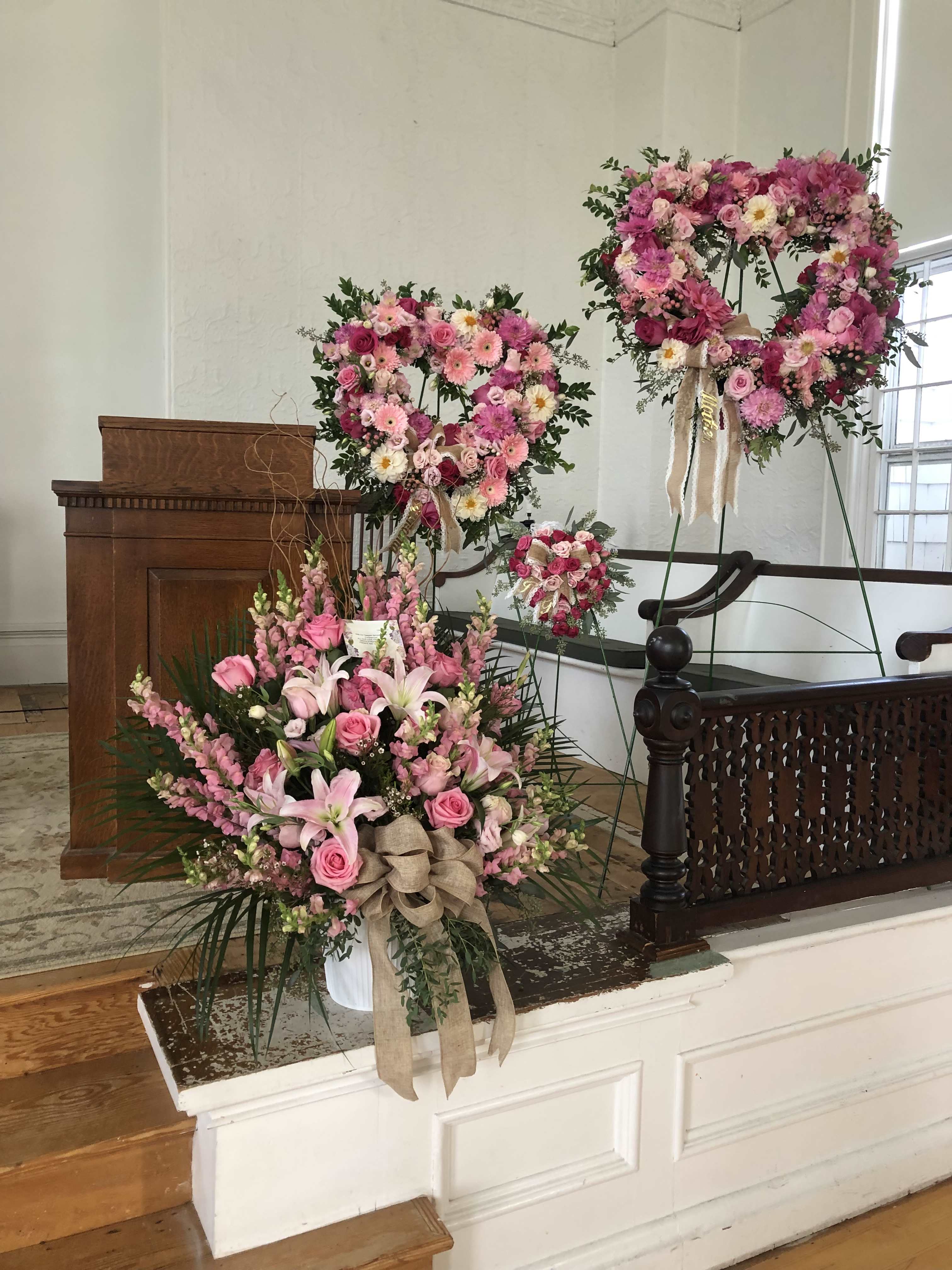Pink floral wreaths and a large bouquet arranged in a church interior