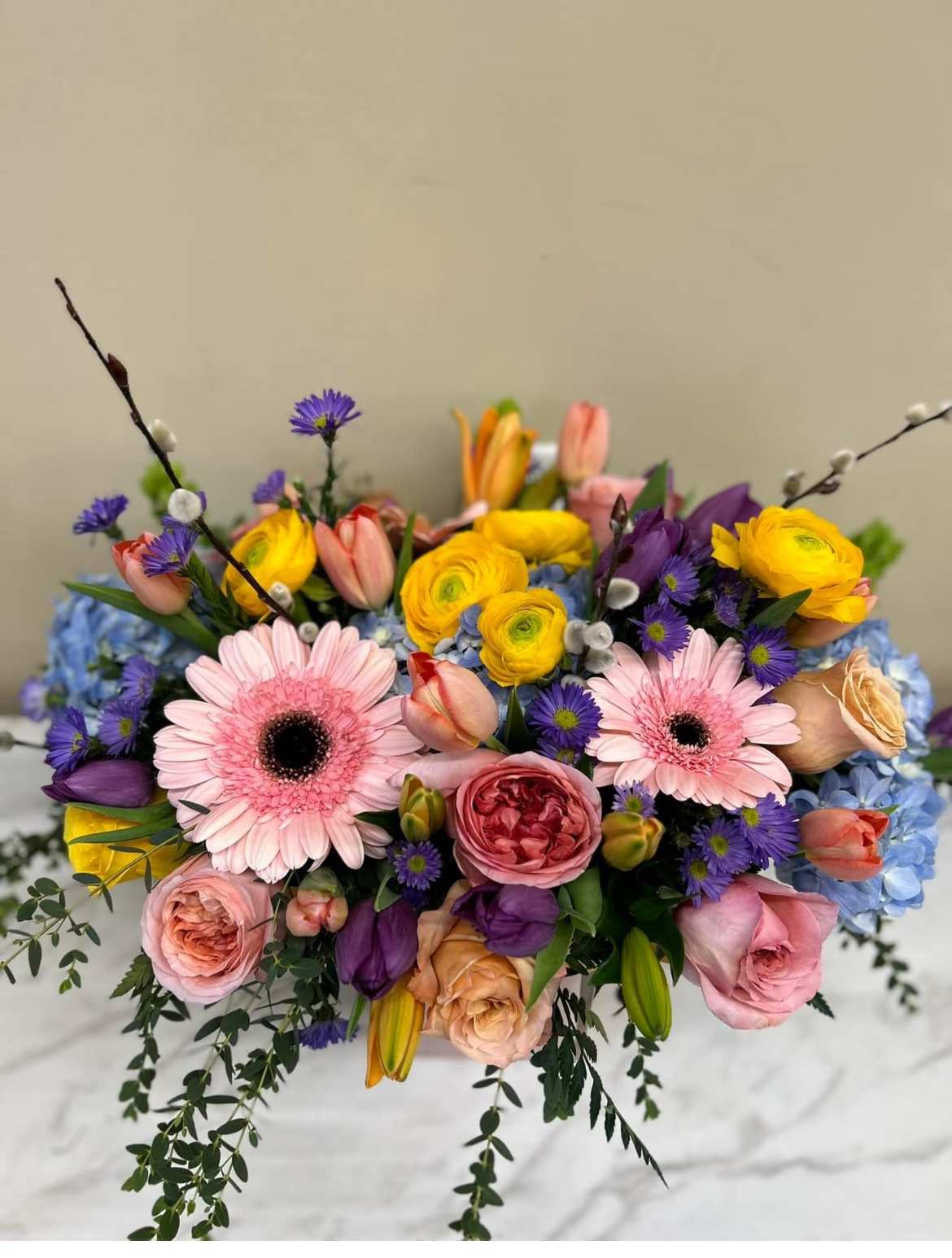 Colorful bouquet with pink gerbera daisies, roses, and yellow ranunculus