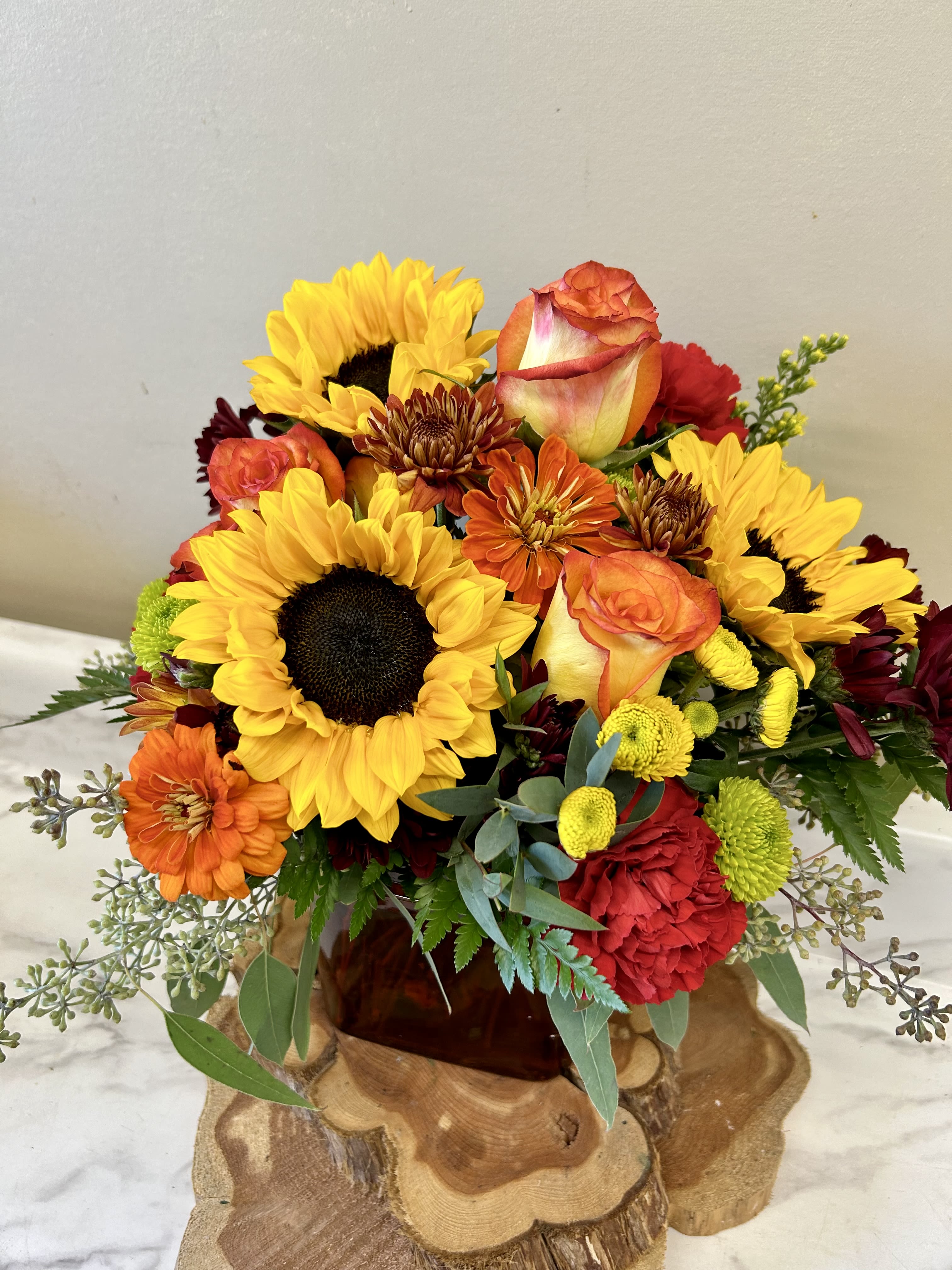 Bouquet of sunflowers, roses, and mums in a glass vase