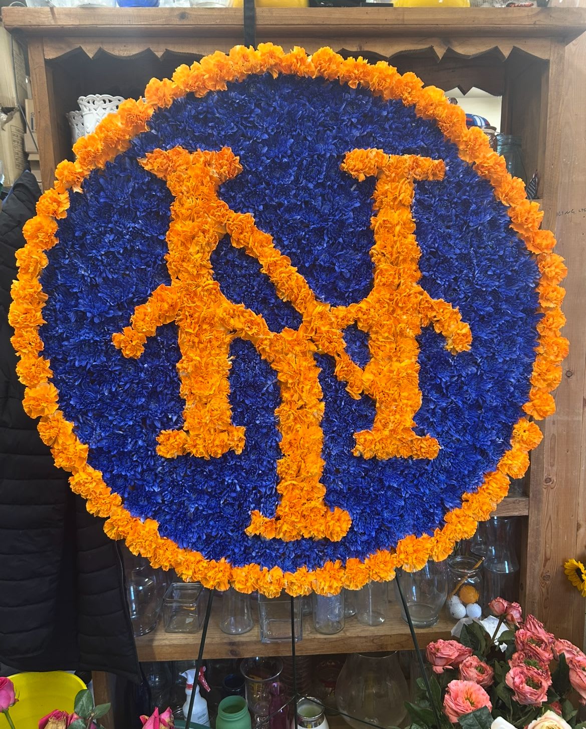 Round floral sign with orange letters on a blue flower background