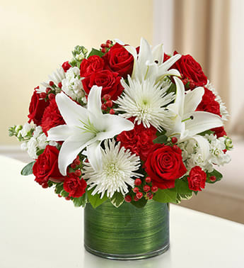 Cherished Memories - Red and White - Product ID: 95403   Convey your caring wishes during times of loss with our graceful red and white sympathy bouquet. Lovely roses, stock, lilies, mums and carnations are hand-crafted in a lovely glass vase to express your heartfelt memories of loved ones who have passed on. Graceful red and white floral arrangement of roses, stock, lilies, spider mums, carnations, hypericum and mini carnations, gathered with variegated pittosporum and salal Hand-designed by our expert florists in a stylish clear glass cylinder vase wrapped with a Ti leaf ribbon; vase measures 6"H Appropriate for the service or the home of friends and family members Large arrangement measures approximately 16"H x 17"L Medium arrangement measures approximately 15"H x 16"L Small arrangement measures approximately 14"H X 15"L Our florists hand-design each arrangement, so colors, varieties, and vase may vary due to local availability Lilies may arrive in bud form and will open to full beauty over the next 2-3 days