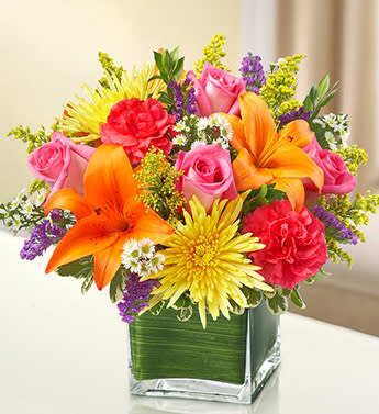 Healing Tears - Multicolor Bright - Product ID: 95437   Send a bright and beautiful expression of your sympathy. A peaceful cube vase arrangement of vibrant roses, lilies, mums, carnations and more says what's in your heart when sent to the home of friends and family or to the memorial service. Elegant arrangement of bright-toned blooms such as roses, lilies, spider mums, carnations, solidago, statice and monte casino, accented with variegated pittosporum and myrtle Artistically designed by our florists in a classic clear glass cube vase lined with a Ti leaf ribbon; vase measures 5"H x 5"D Appropriate for the service or for sending to the home or office of friends and family members Large arrangement measures approximately 11"H x 11"L Medium arrangement measures approximately 10"H x 10"L Small arrangement does not include roses and measures approximately 9"H x 9"L Our florists hand-design each arrangement, so colors, varieties, and container may vary due to local availability Lilies may arrive in bud form and will open to full beauty over the next 2-3 days