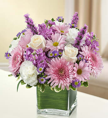Healing Tears - Lavender and White - Product ID: 95420  Let the comforting beauty of elegant lavender and white blooms send a caring message of your sympathies. Lovely roses, stock, liatris, cremones, carnations and more are gathered by hand in a classic cube vase and sent to the home or service to honor lost loved ones. Elegant lavender and white arrangement of roses, stock, liatris, cremones, carnations, daisy poms and monte casino, accented with variegated pittosporum Artistically designed by our florists in a classic clear glass cube vase lined with a Ti leaf ribbon; vase measures 5"H x 5"D Appropriate for the service or for sending to the home or office of friends and family members Large arrangement measures approximately 11"H x 11"L Medium arrangement measures approximately 10"H x 10"L Small arrangement does not include roses and measures approximately 9"H x 9"L Our florists hand-design each arrangement, so colors, varieties, and container may vary due to local availability