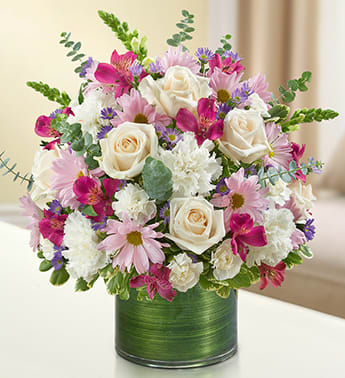 Cherished Memories - Lavender and White - Product ID: 95421   Remember a loved one with elegance and grace by sending our peaceful lavender and white arrangement in a classic cylinder vase. The freshest roses, snapdragons, alstroemeria, carnations and more are gathered by our florists to offer a tribute to a beautiful life. Graceful lavender and white arrangement of roses, snapdragons, alstroemeria, carnations, daisy poms, mini carnations and monte casino, gathered with variegated pittosporum and spiral eucalyptus Hand-designed by our expert florists in a stylish clear glass cylinder vase wrapped with a Ti leaf ribbon; vase measures 6"H Appropriate for the service or the home of friends and family members Large arrangement measures approximately 16"H x 17"L Medium arrangement measures approximately 15"H x 16"L Small arrangement measures approximately 14"H X 15"L Our florists hand-design each arrangement, so colors, varieties, and vase may vary due to local availability