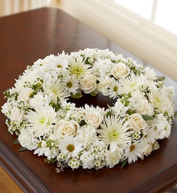 Cremation Wreath - All White - Product ID: 95381   Our beautiful cremation wreath offers an elegant way to honor your loved oneâs memory. Crafted from the freshest white roses, stock, spider mums, carnations, daisy poms and monte casino, this table wreath is open at the center to place a photograph or cremation urn as a tasteful tribute. Comforting table wreath arrangement of white roses, stock, spider mums, carnations, daisy poms and monte casino, gathered with variegated pittosporum and seeded eucalyptus Hand-crafted by our select florists to be sent to the cremation service to honor friends or family members Also appropriate for smaller memorial services in the home The cremation urn or a framed photograph can be placed in the center to present a lovely tribute at the service or home Large arrangement measures approximately 22"H x 22"L Small arrangement measures approximately 17"H x 17"L Our florists hand-design each arrangement, so colors and varieties may vary due to local availability
