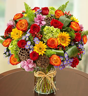 Garden of Grandeur for Fall - Product ID: 99170  We've taken one of our most impressive bouquets and filled it with lots of rich color and texture for Fall. Vibrant red and bi-color roses, brilliant sunflowers and cheery purple monte casino are gathered with unique accents in a chic glass cylinder vase to turn any birthday, anniversary or Autumn day into a "grand" celebration! Gathering of red and bi-color yellow roses, sunflowers, dried lotus pods, aspidistra leaves, kale, mini hydrangeas, hypericum, monte casino and more Hand-designed by our expert florists in a clear glass cylinder vase tied with raffia; measures 8"H Large arrangement measures approximately 21"H x 16"L Medium arrangement measures approximately 20.5"H x 15"L Small arrangement measures approximately 20"H x 14"L Our florists hand-design each arrangement, so colors, varieties and container may vary due to local availability