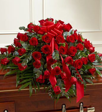 Large red rose casket spray with red ribbons and greenery