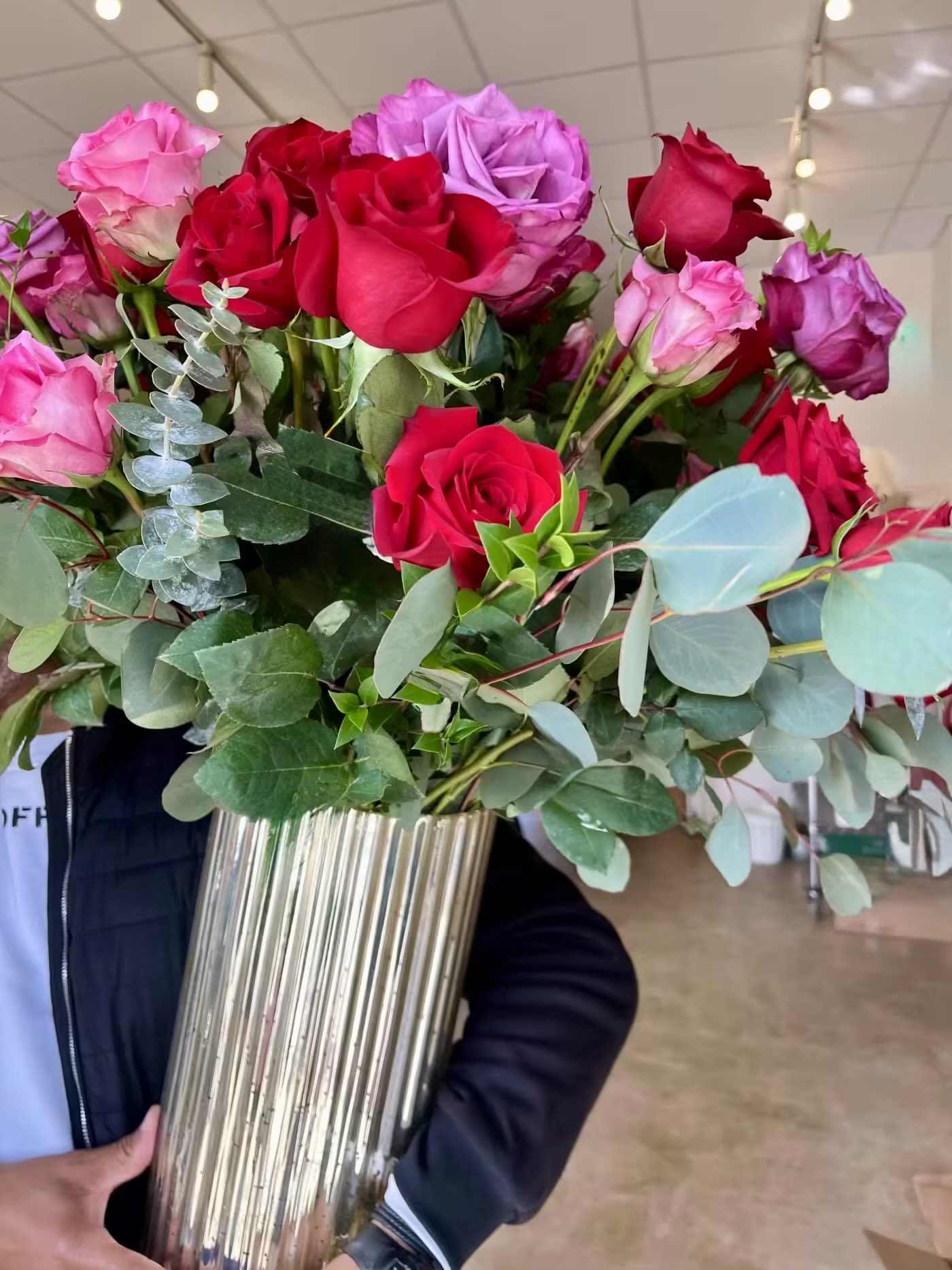 Bouquet of red, pink, and purple roses in a tall metallic vase