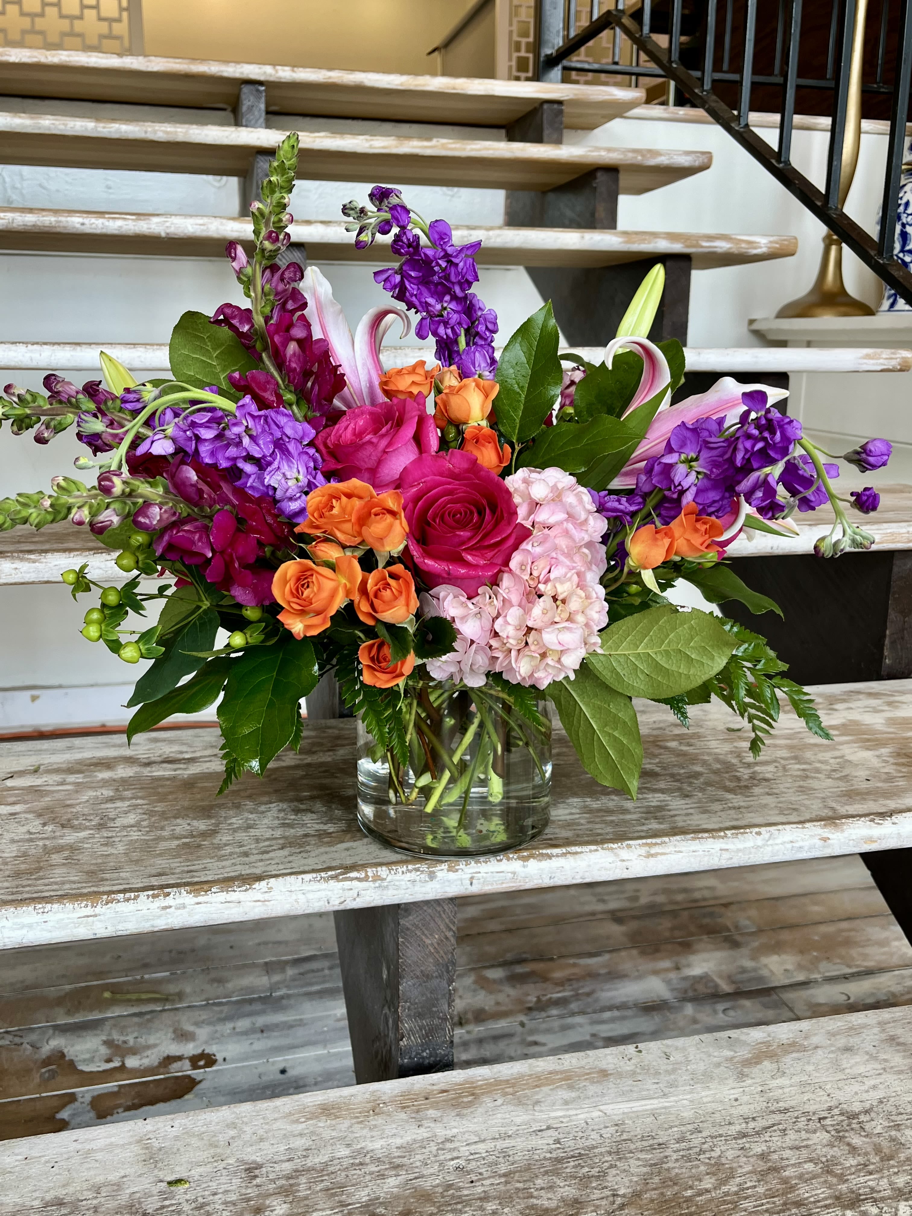 Mixed bouquet of pink, orange, and purple flowers in a glass vase