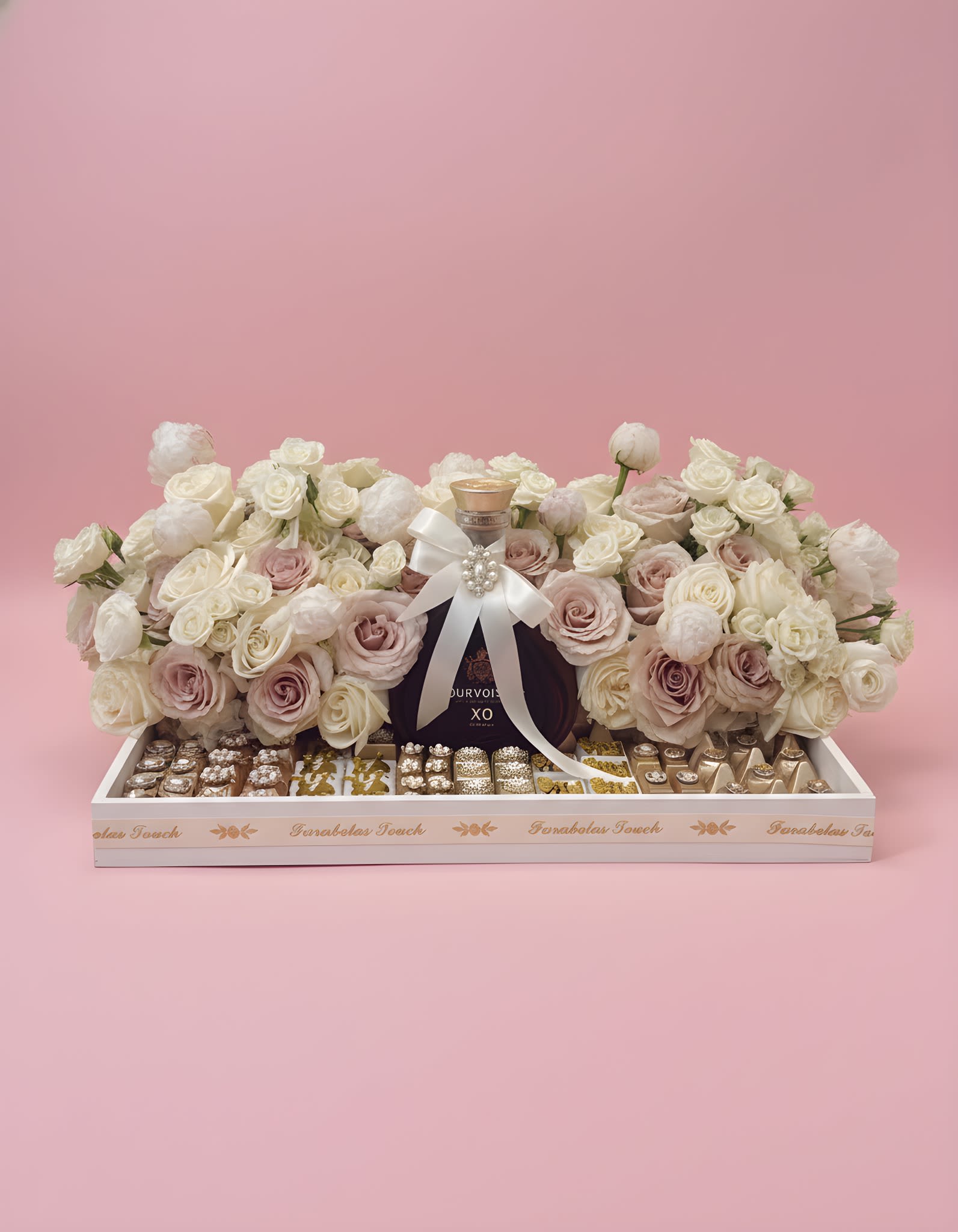 Rosé Royale Luxury Tray -  Chocolate &amp; Bottle NOT included  An unforgettable statement of elegance featuring lush ivory and blush roses, delicate peonies, premium gourmet chocolates, and an exquisite bottle of Courvoisier XO Cognac, beautifully presented in a keepsake luxury tray. Finished with a satin bow and jeweled accent, this sophisticated gift is designed to celebrate life’s most memorable occasions in timeless style.