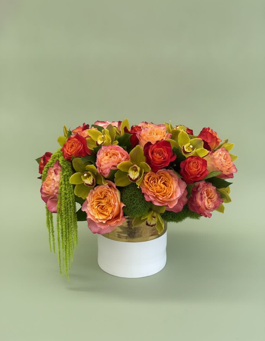 Sunset Orchid Luxe - A striking luxury arrangement featuring premium garden roses in warm sunset shades, vibrant orange roses, elegant green cymbidium orchids, lush green trick dianthus, and cascading hanging amaranthus, artfully designed in a modern white-and-gold keepsake vase. Rich in texture, color, and movement, this sophisticated design makes an unforgettable statement for birthdays, anniversaries, congratulations, housewarmings, or simply to brighten someone’s day