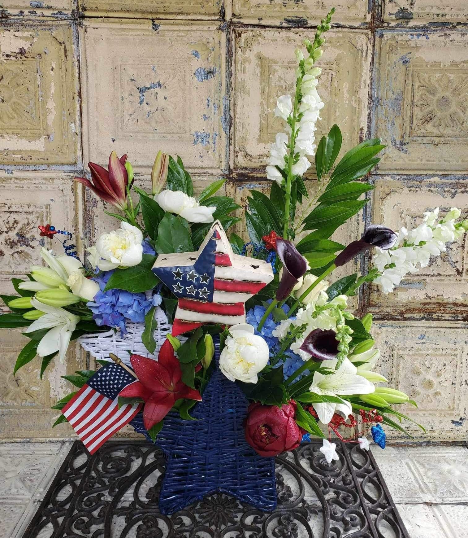 Patriotic floral arrangement in a star-shaped basket with an American flag