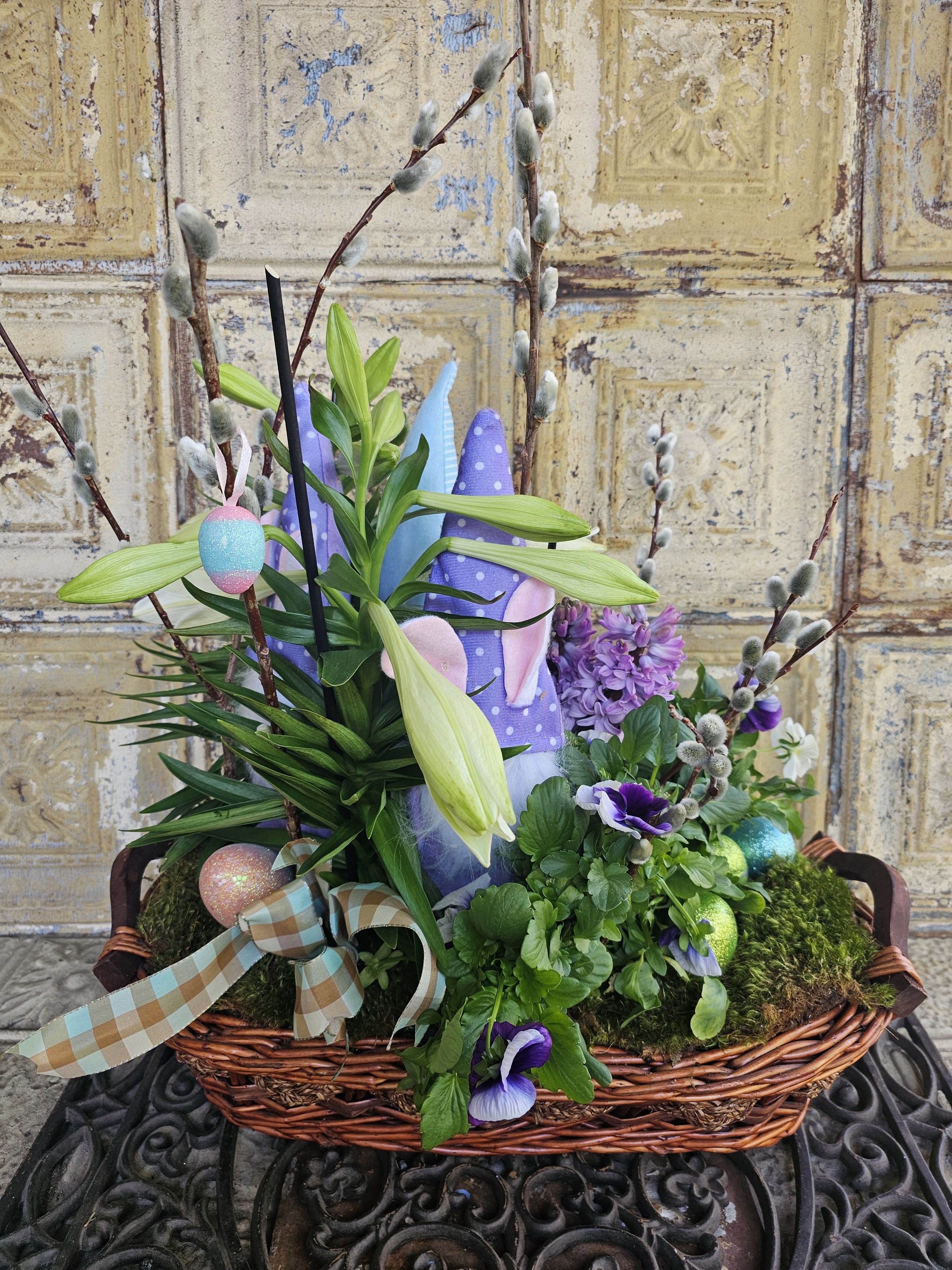 Easter basket with lilies, purple flowers, and decorated eggs
