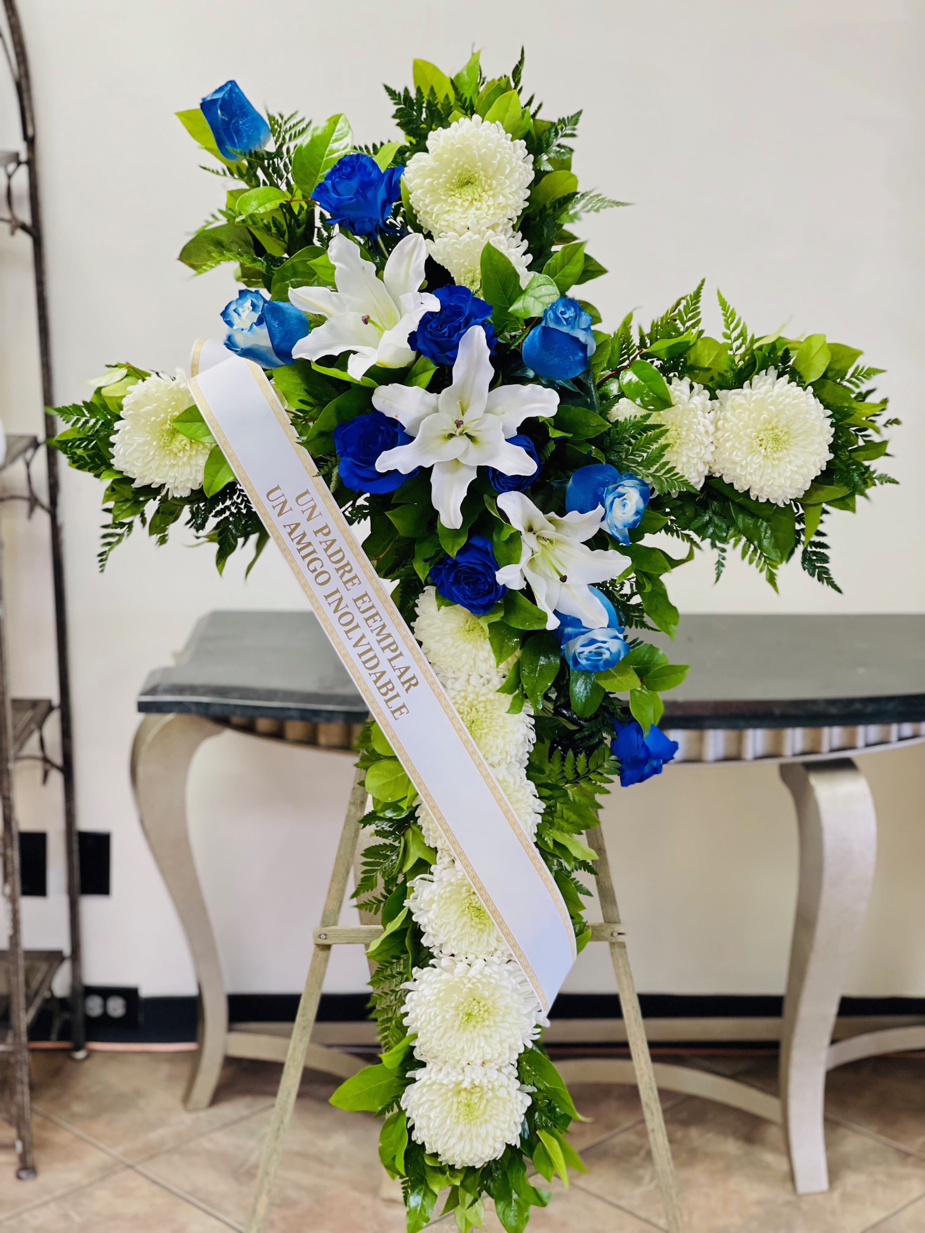 Blue and white funeral spray with a memorial ribbon