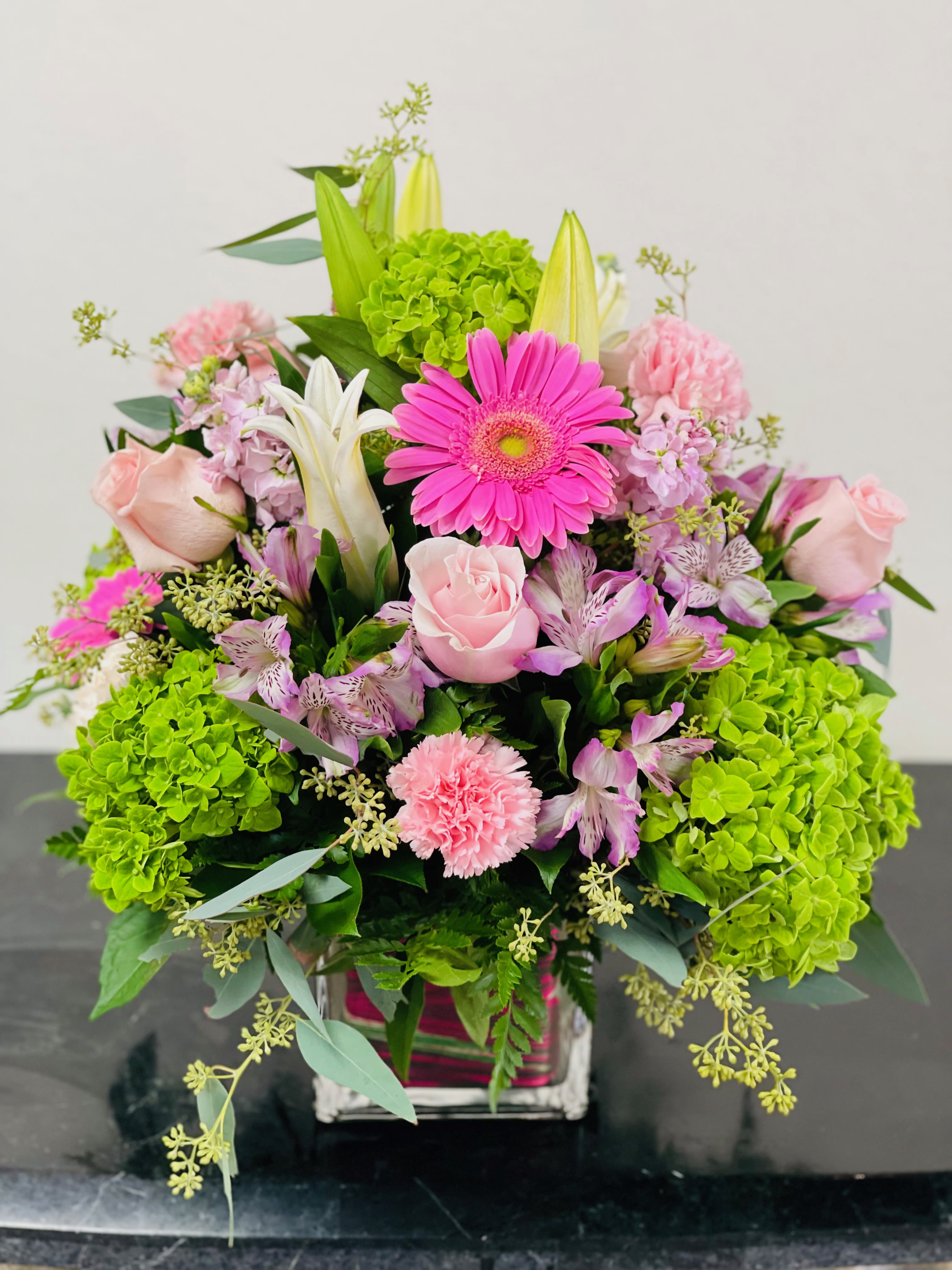 Pink and white mixed flower arrangement with bright green hydrangeas in a vase