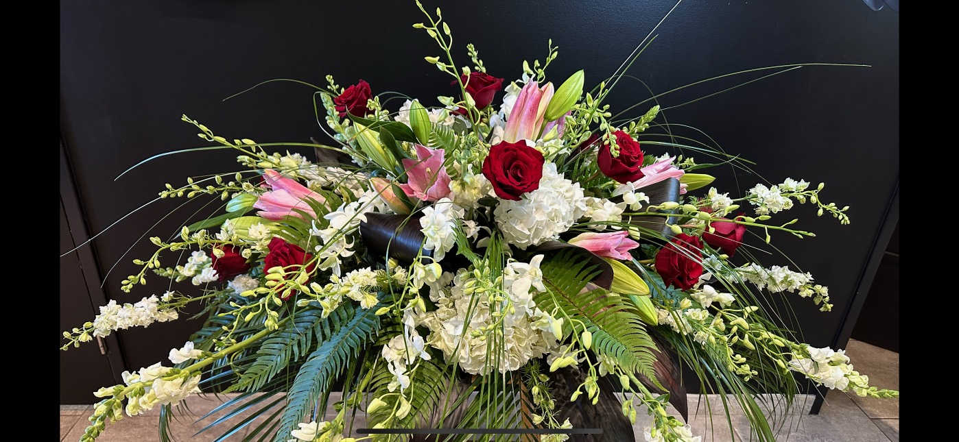 Large floral arrangement with red roses, pink lilies, and white blooms