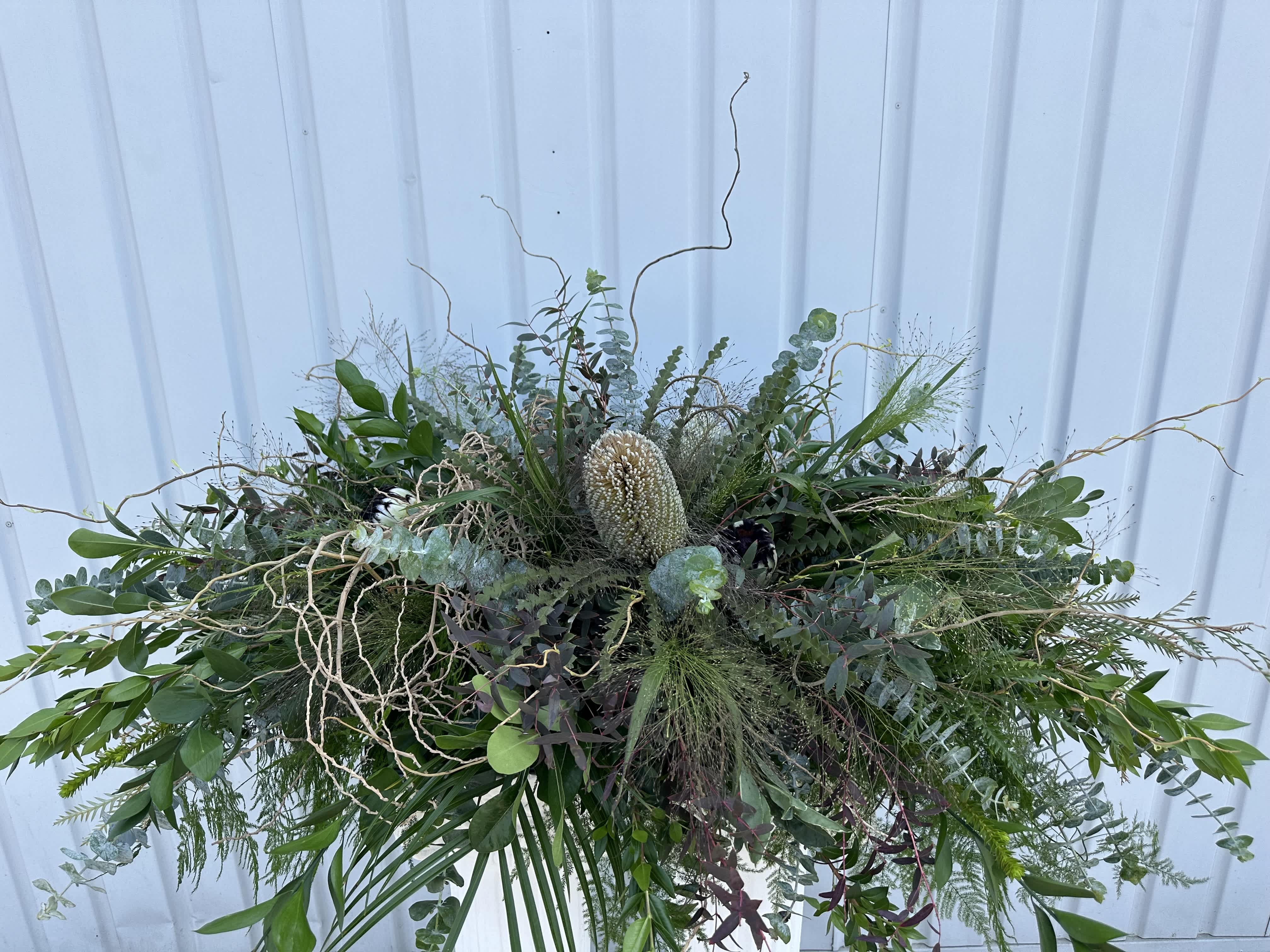 Large greenery arrangement with a central cream protea-like bloom