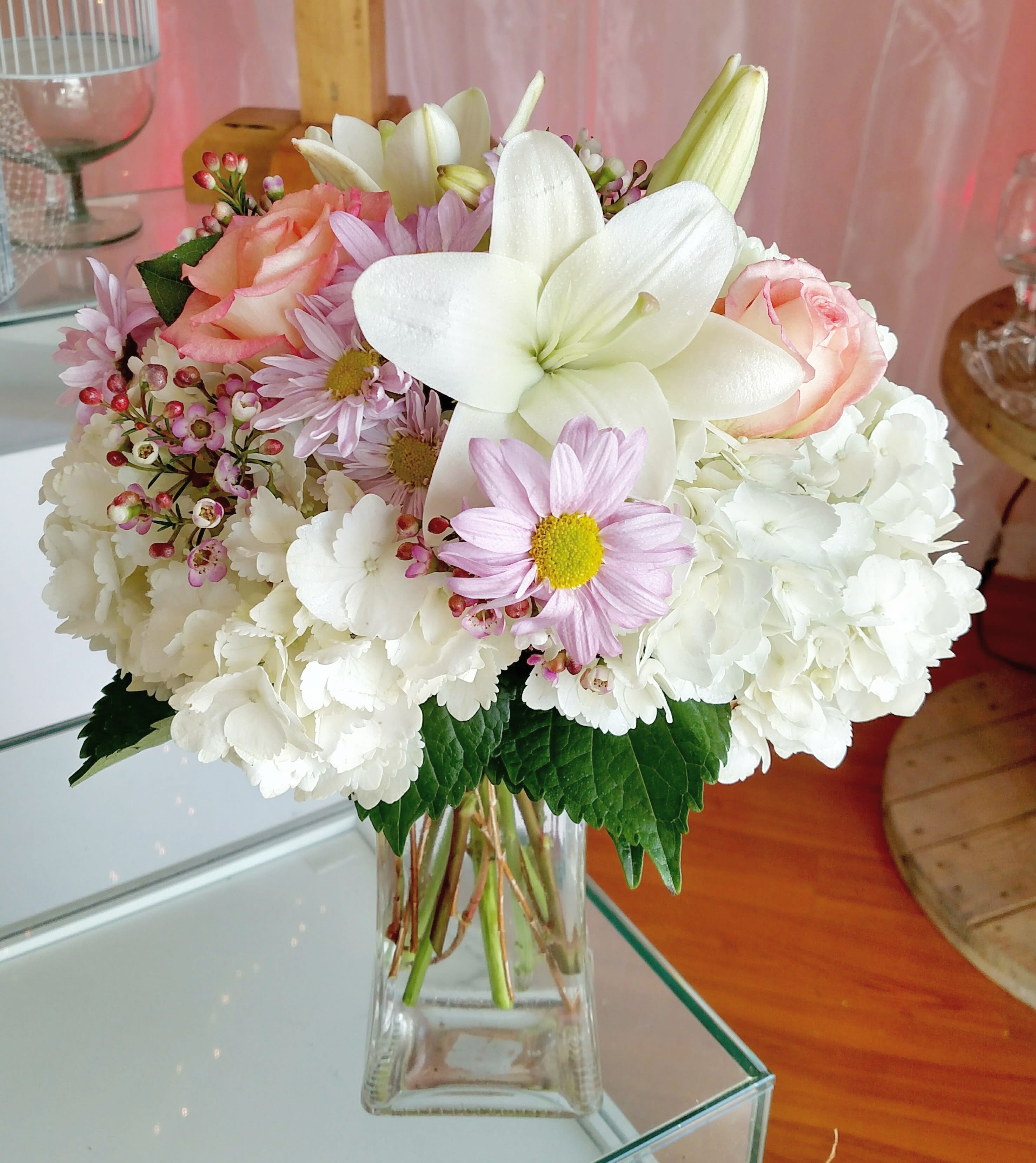 Bouquet of white hydrangeas, pink roses, and lilies in a clear glass vase