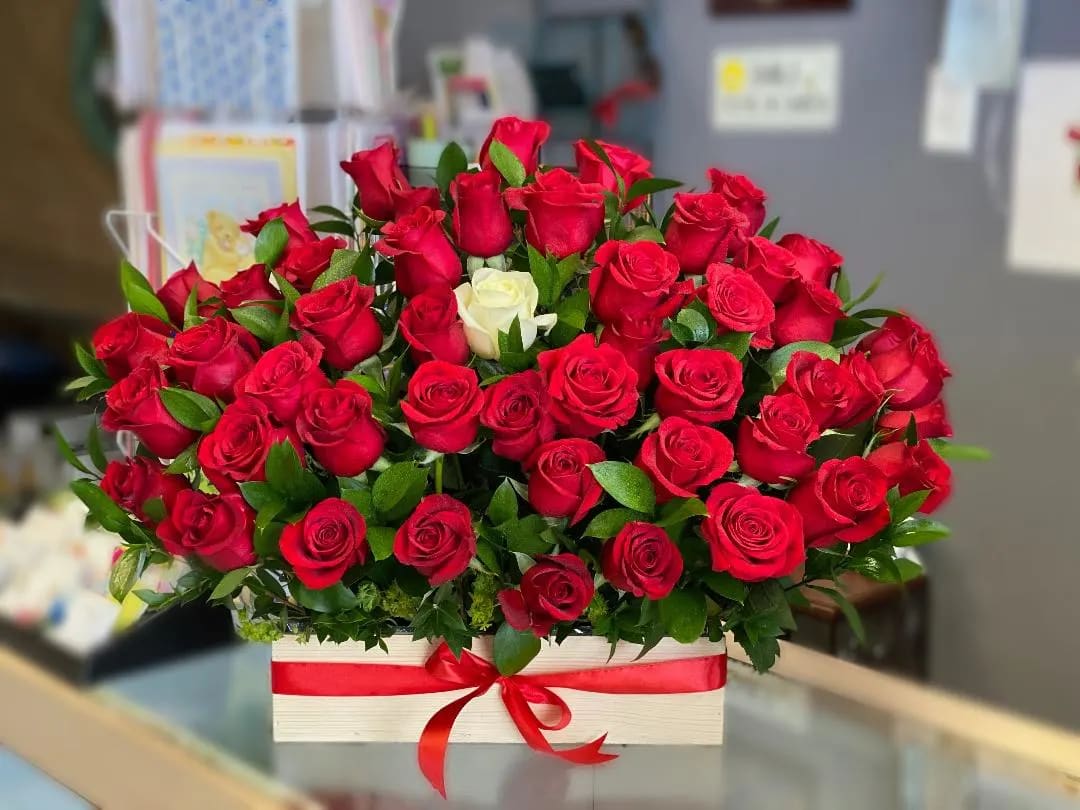 Red roses arranged in a white box with a red ribbon