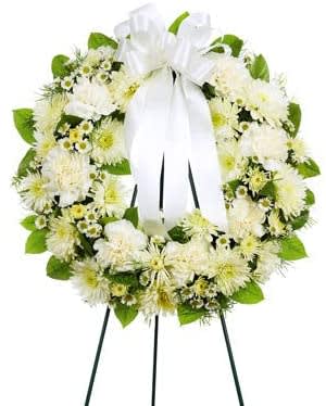 White floral wreath with a large white ribbon on a stand