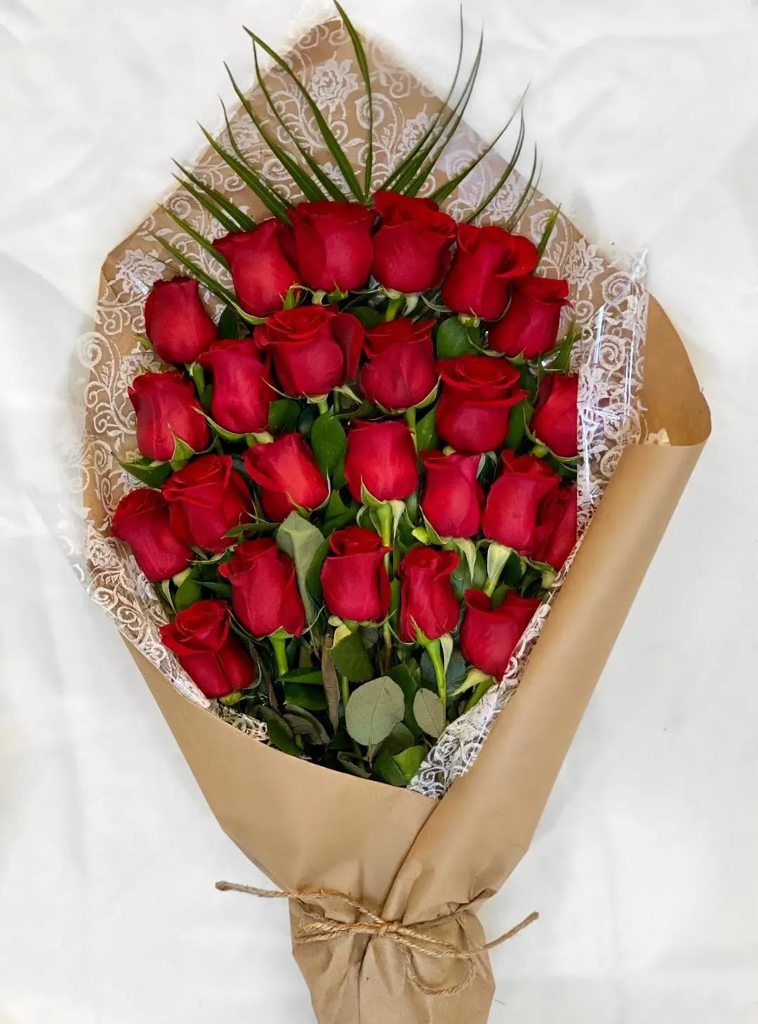 Bouquet of red roses wrapped in brown paper with lace trim