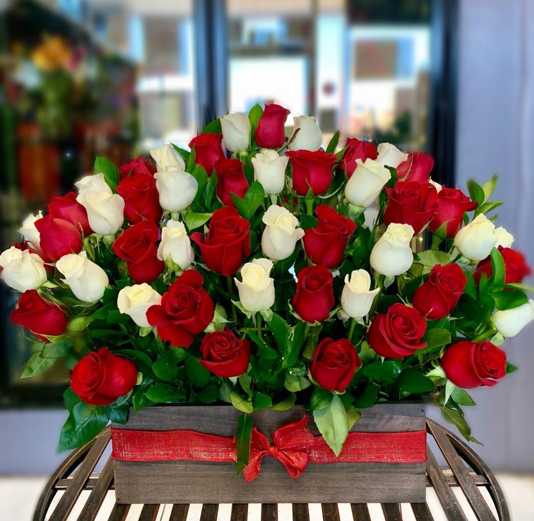 Red and white roses arranged in a rectangular box with a red ribbon