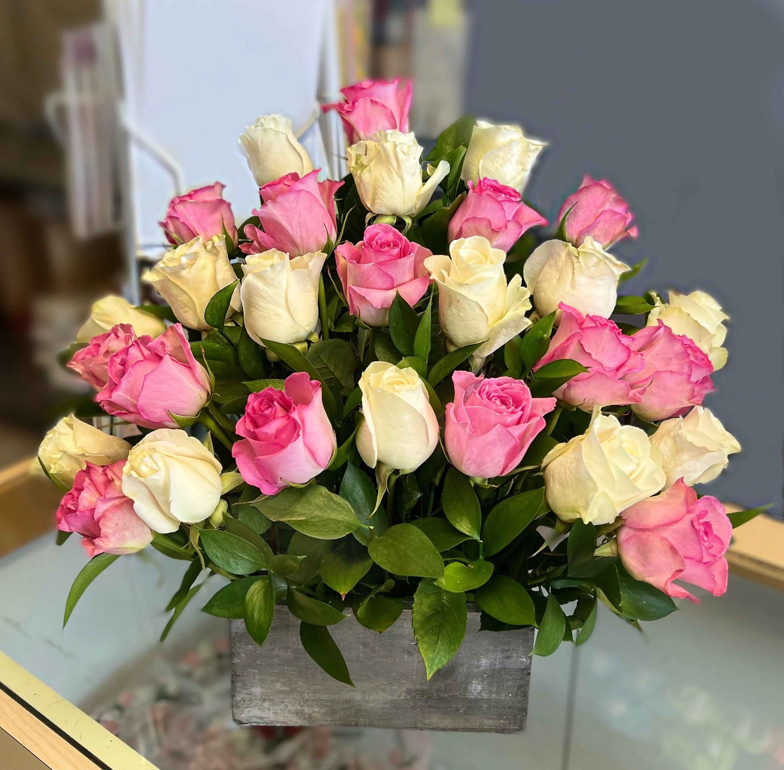 Pink and white roses arranged in a gray rectangular vase
