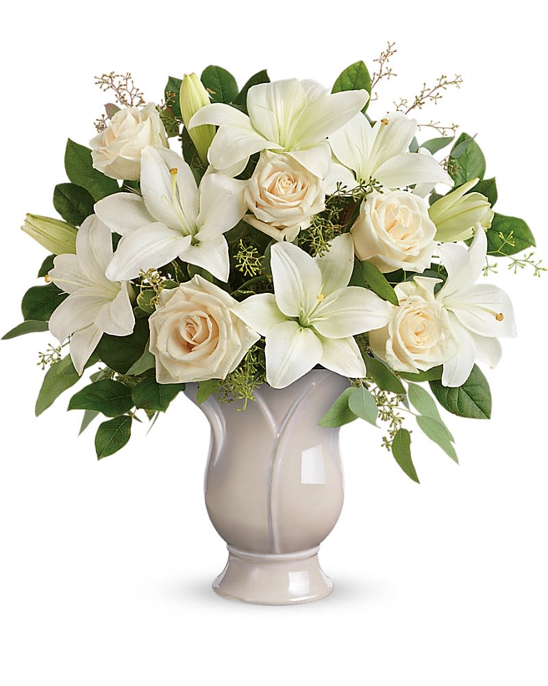 White lilies and cream roses arranged in a beige vase
