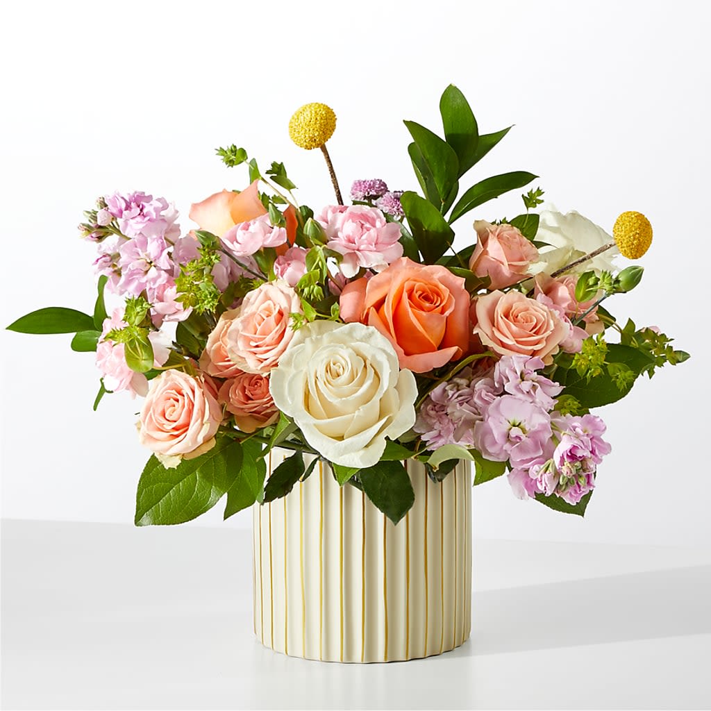 French Market in Ivory Vase - Perfect for birthdays, a thank you, housewarmings, and so much more, our French Market Bouquet brings timeless charm into their space.  2 Pink Stock stems 2 Ivory 50 cm Roses 2 Pink Mini Carnation stems 2 Coral 50 cm Roses 1 Lavender Button Pompon stem 1 Bupleurum stem 2 Peach Spray Rose stems 2 Craspedia stems 3 Salal tips 2 Israeli Ruscus