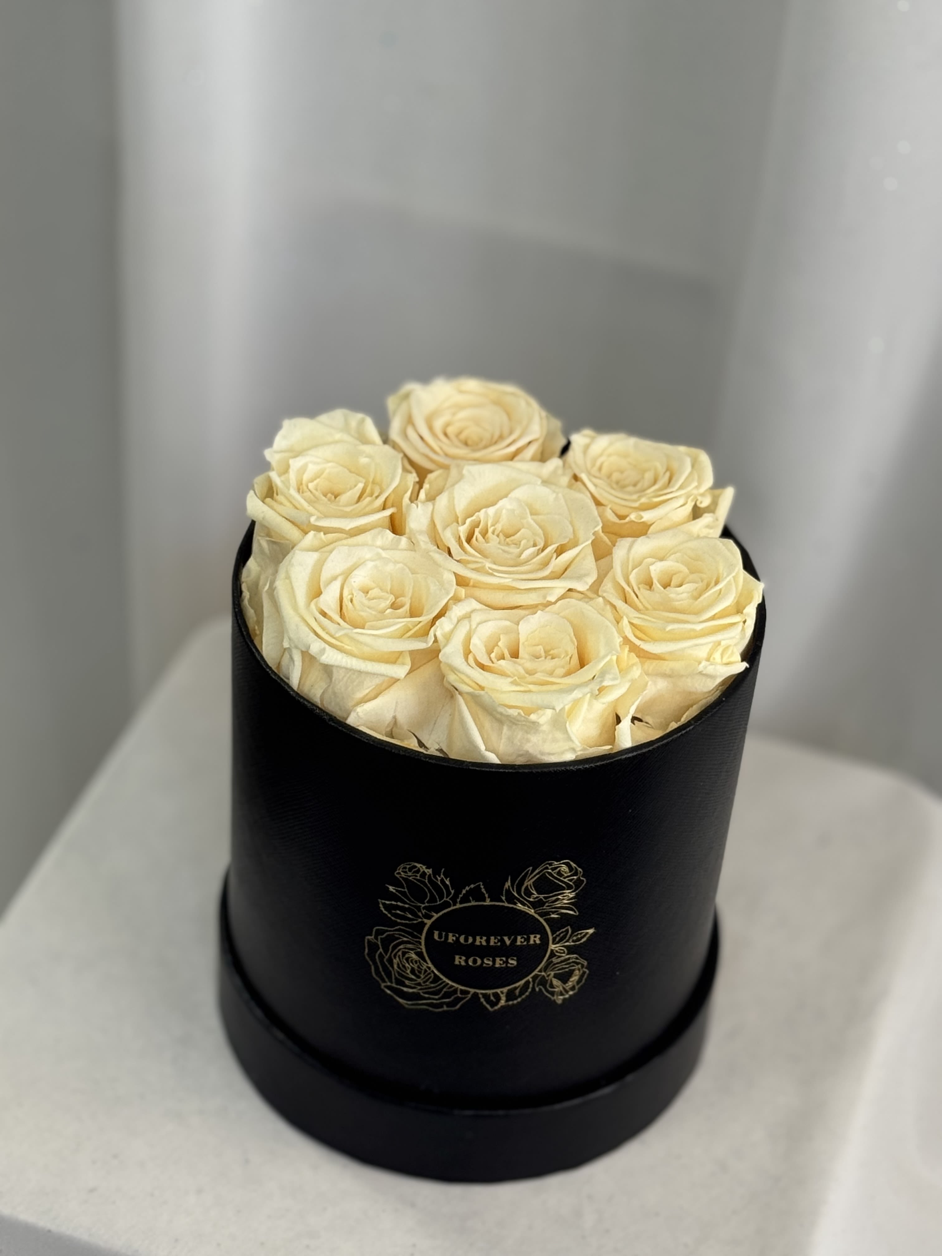 Cream roses arranged in a black round box