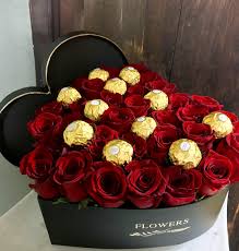 Heart-shaped box filled with red roses and gold-wrapped chocolates