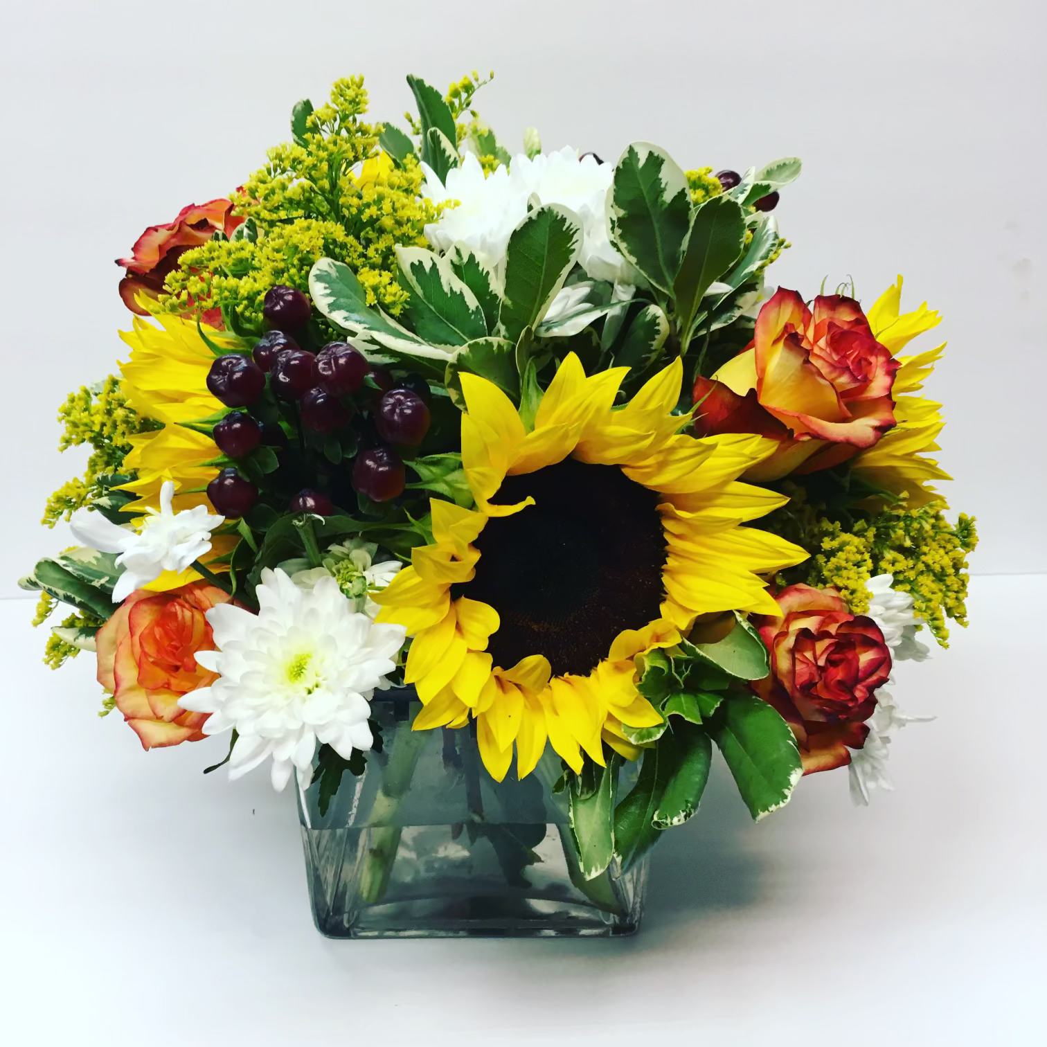 Sunflower and rose bouquet in a square glass vase