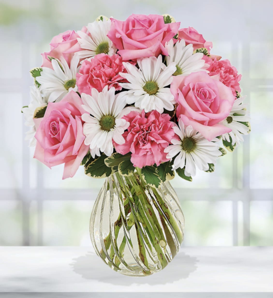 Pink roses and white daisies in a clear glass vase