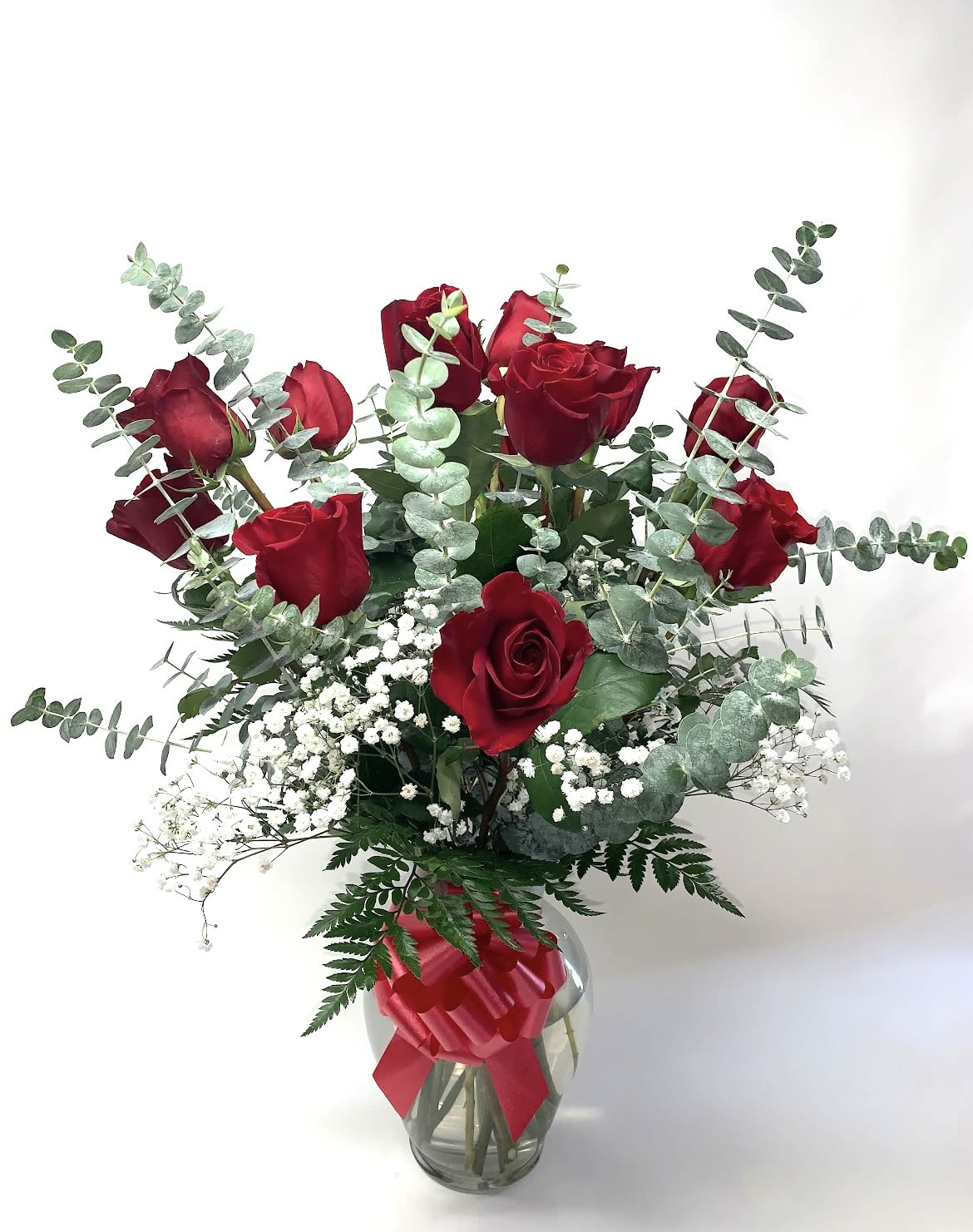 Red roses with baby's breath and eucalyptus in a glass vase with a red ribbon