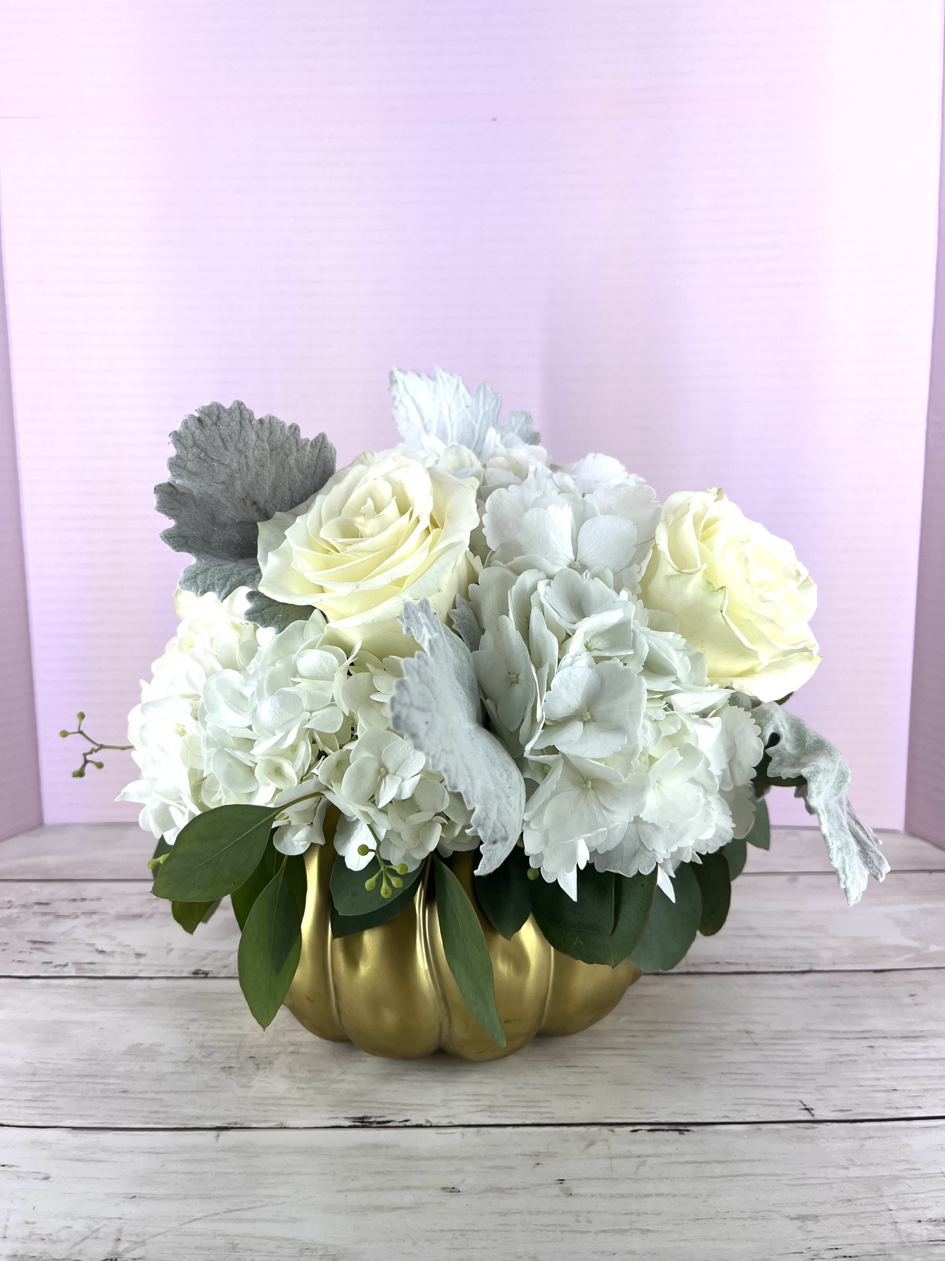 White roses and hydrangeas in a gold pumpkin vase