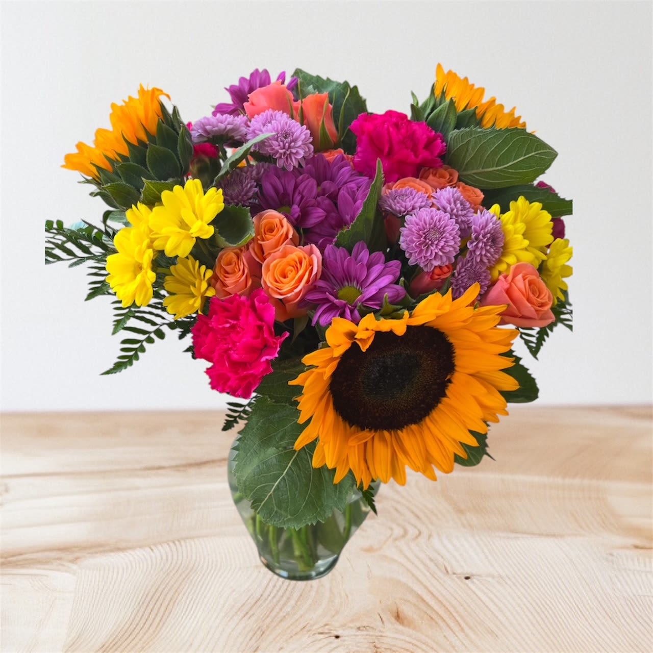 Mixed bouquet with sunflowers, roses, and chrysanthemums in a glass vase